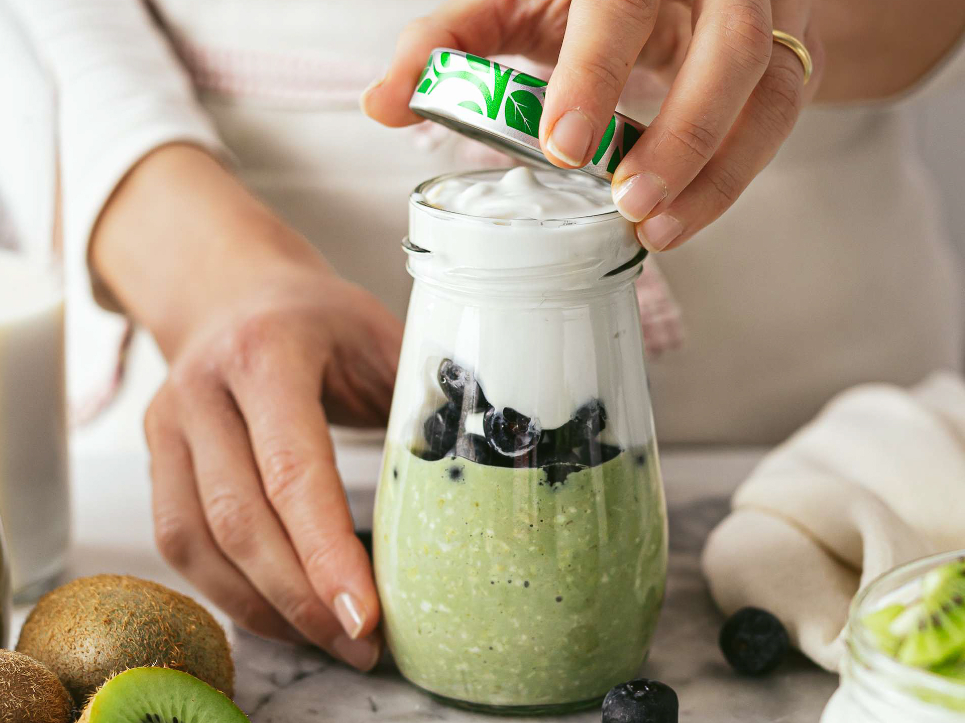 a jar with matcha oats blueberries and yogurt