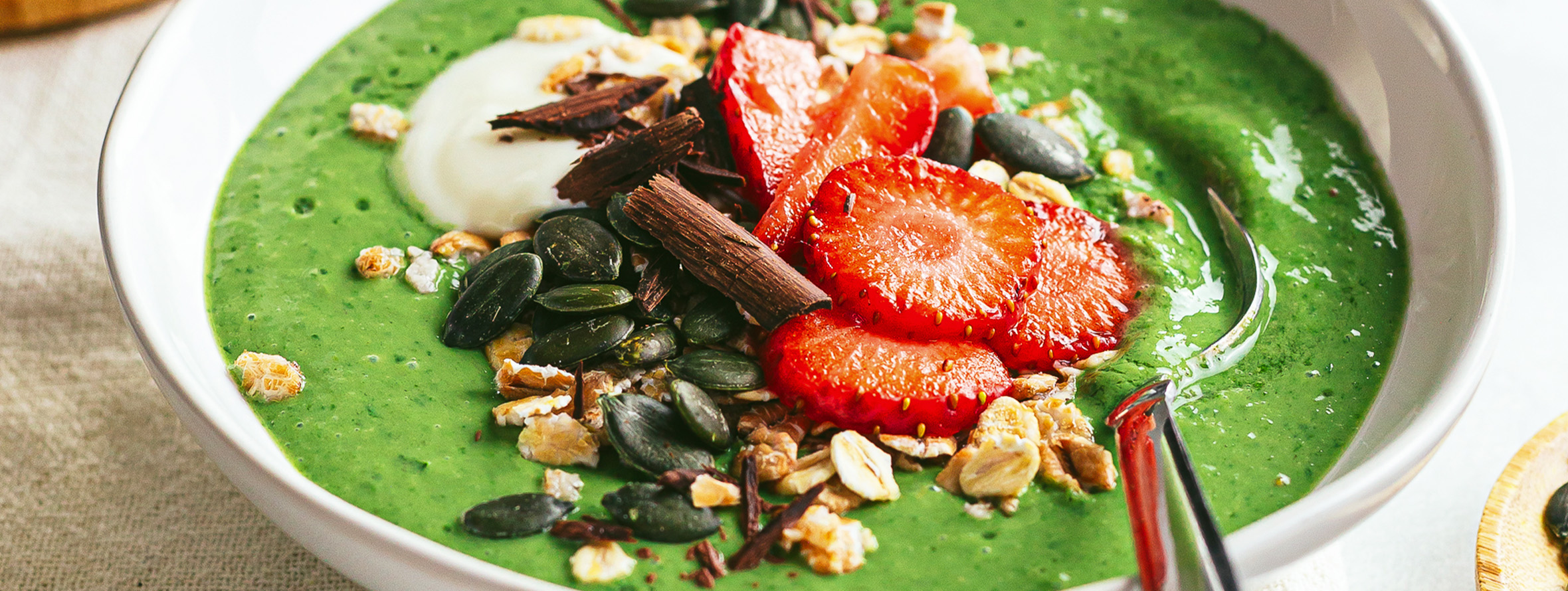 green spinach smoothie bowl with strawberries and oats