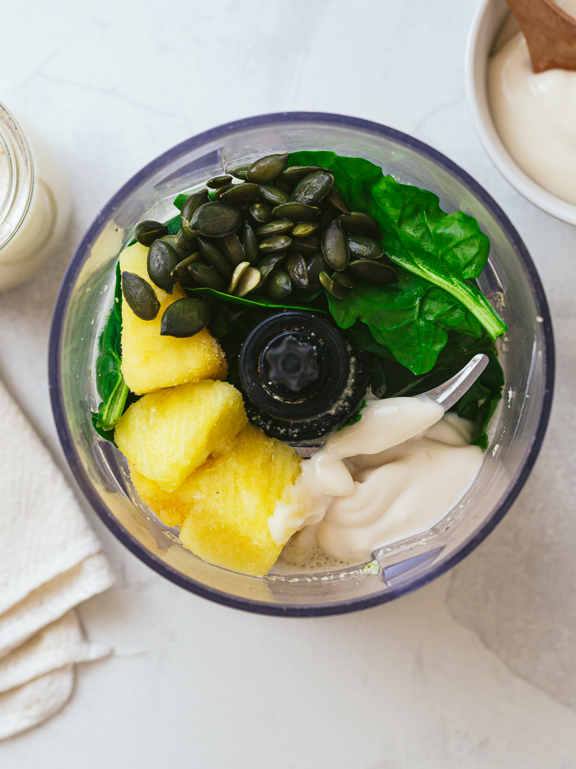 blender with pineapple, spinach, yoghurt and pumpkin seeds