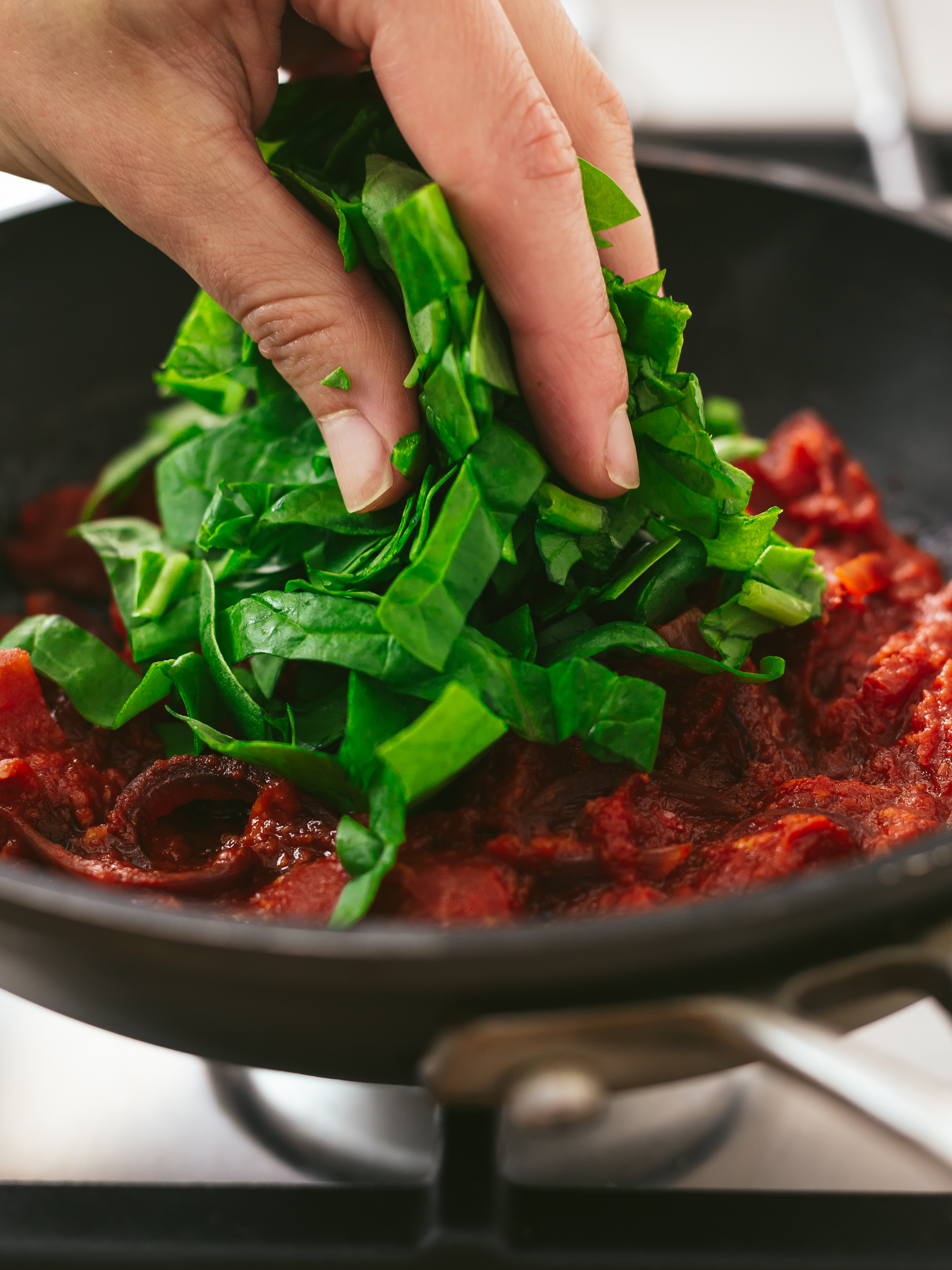 chopped spinach added to spicy tomato sauce 