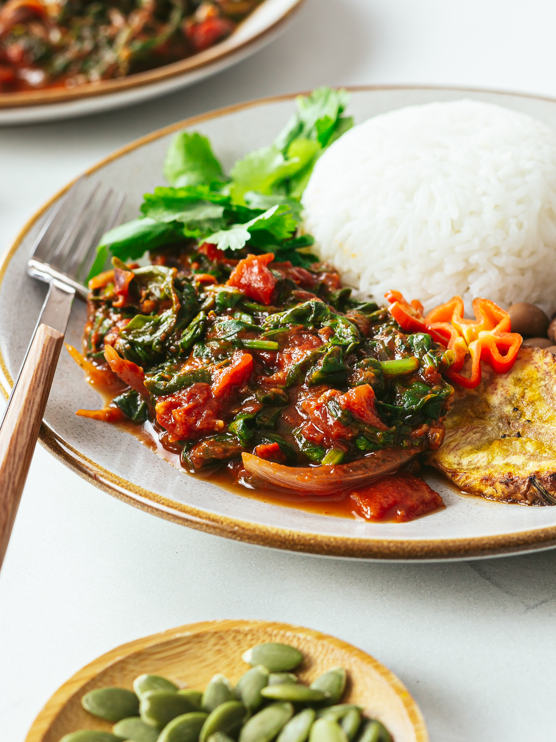 african spinach stew with rice and plantain in a plate