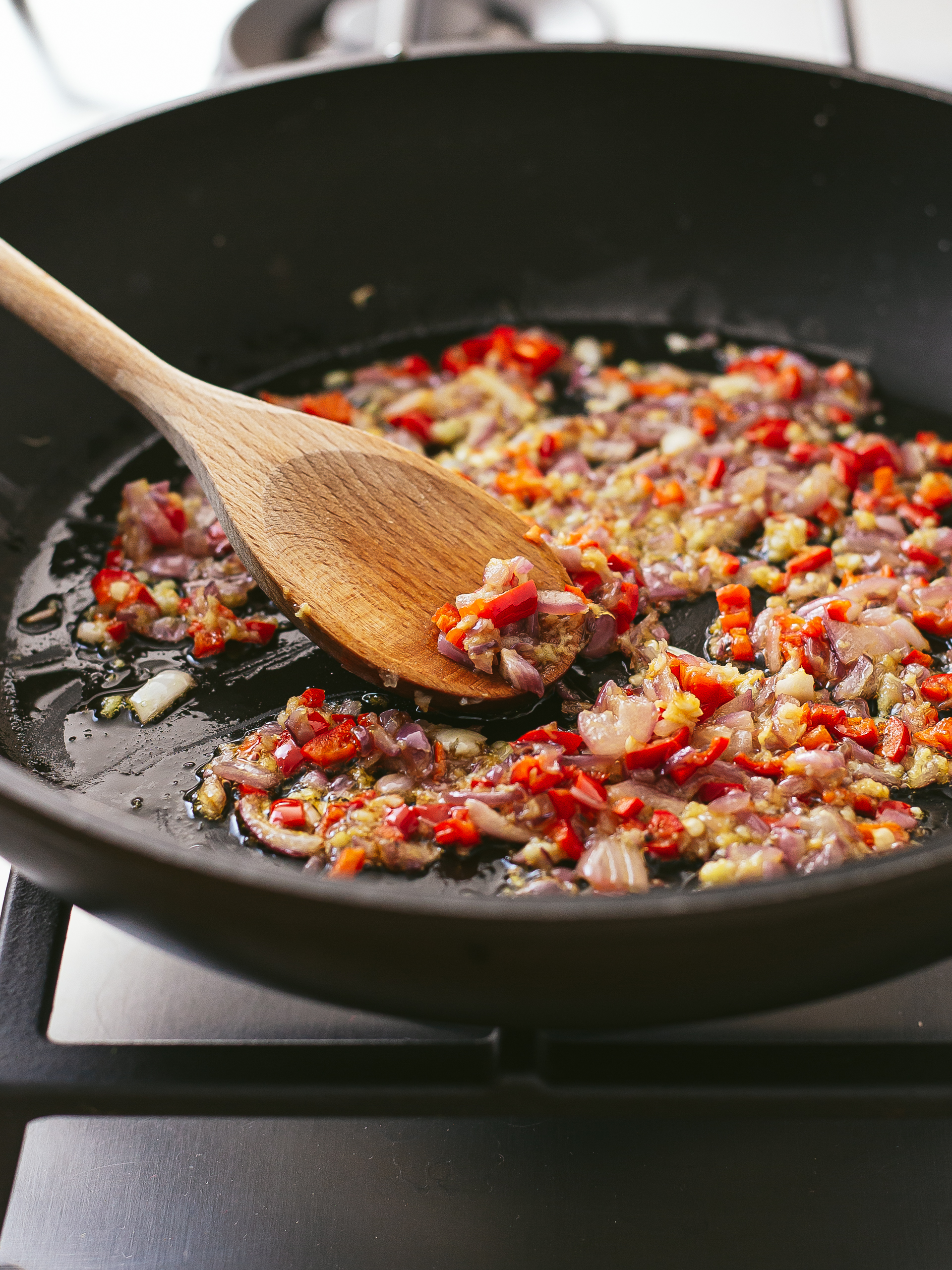 chillies, ginger, garlic, and onions frying in a skillet
