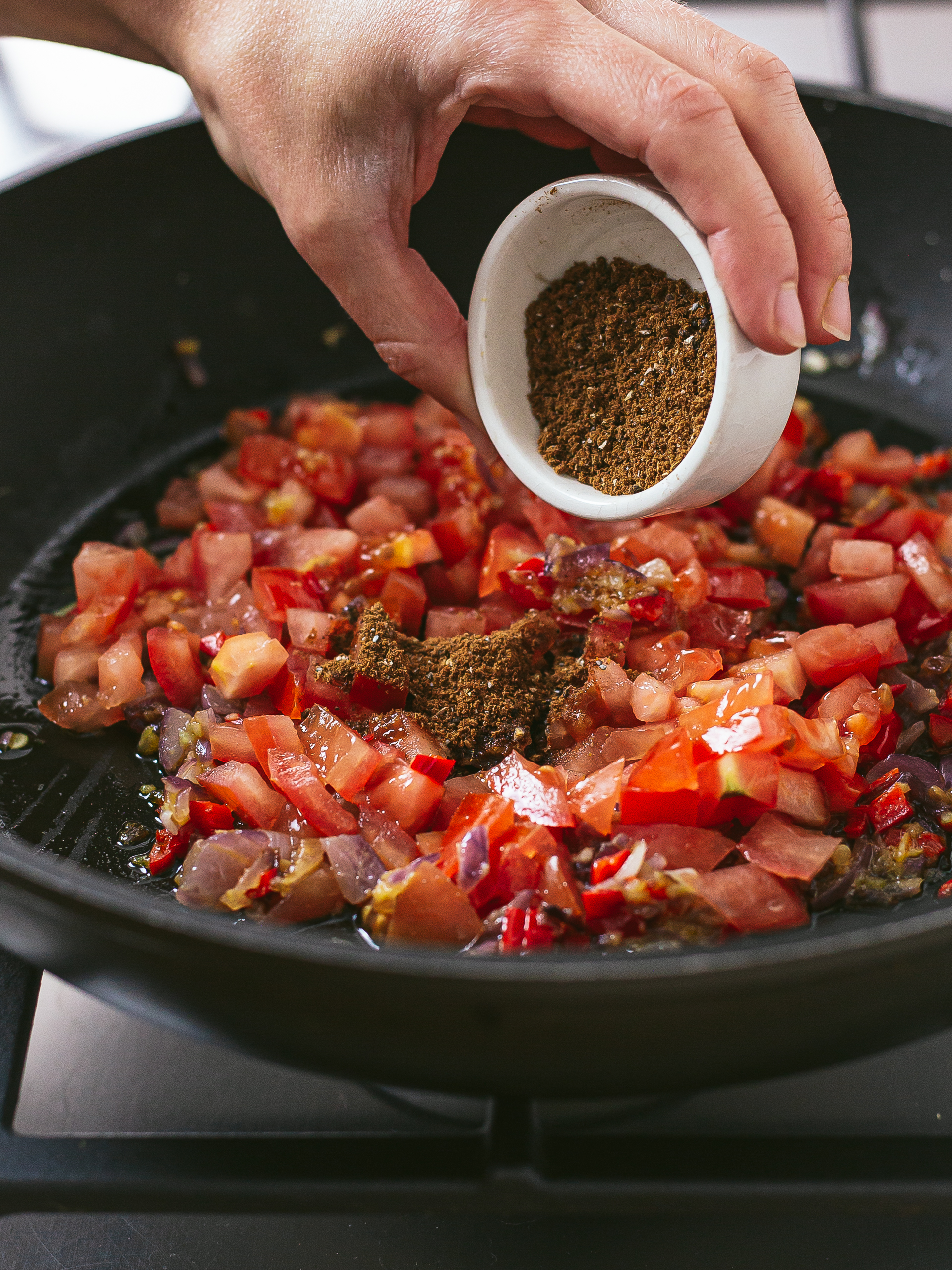 chopped tomatoes cooking in a pan with pilau rice spices