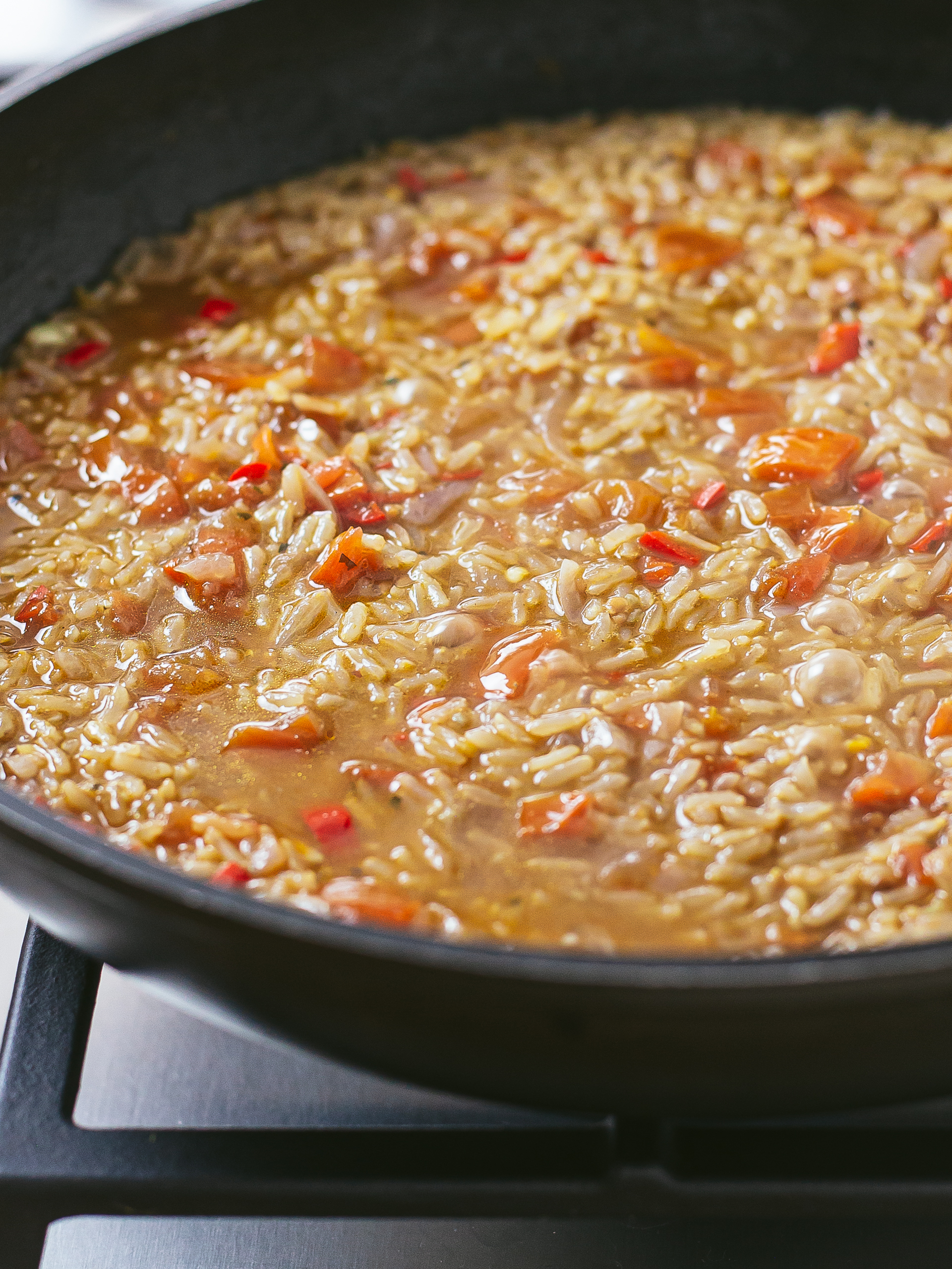 kenyan pilau rice cooking in a pan with tomatoes, chillies, and spices