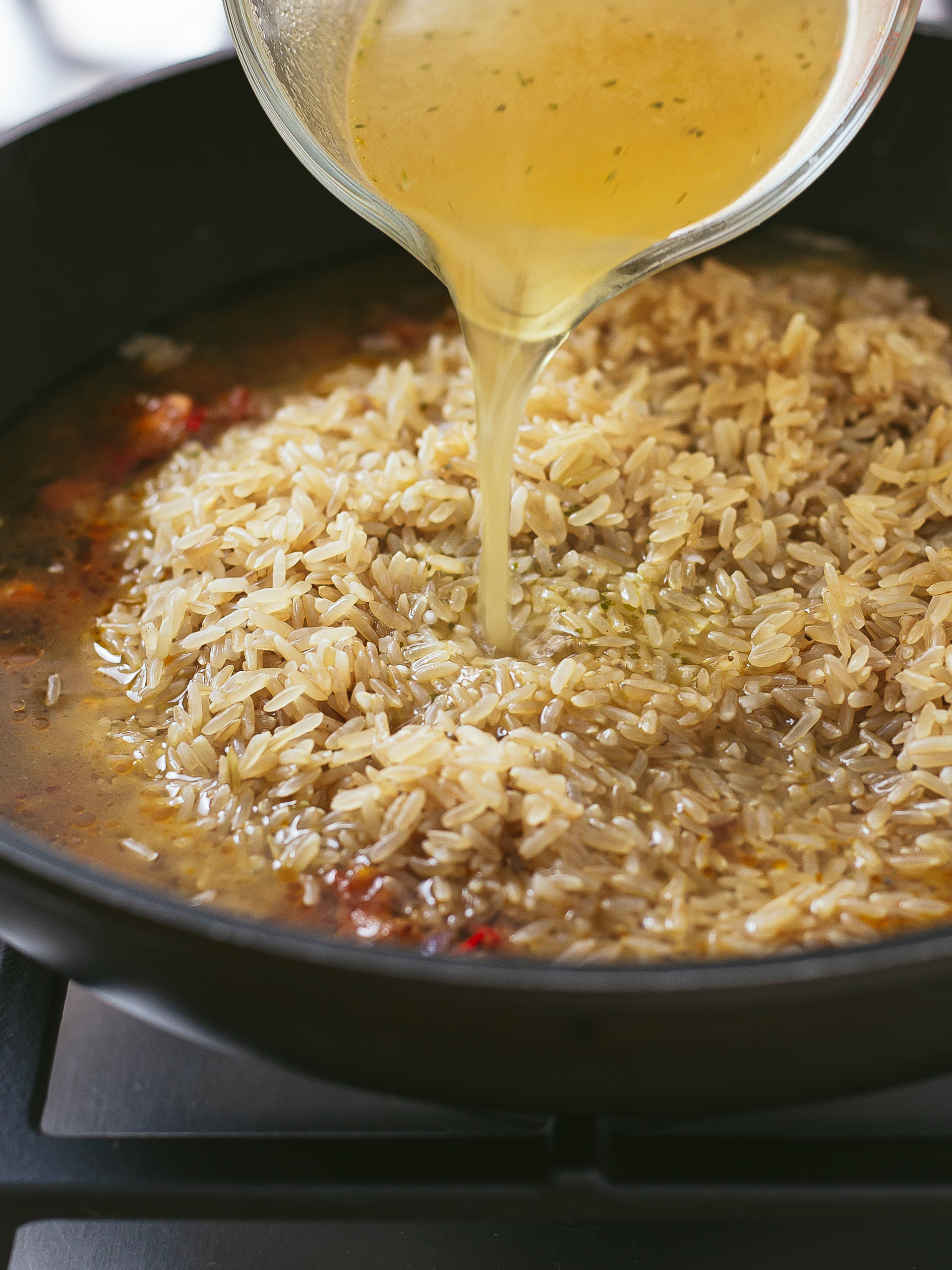 long grain brown rice in a pan with vegetable stock for pilau