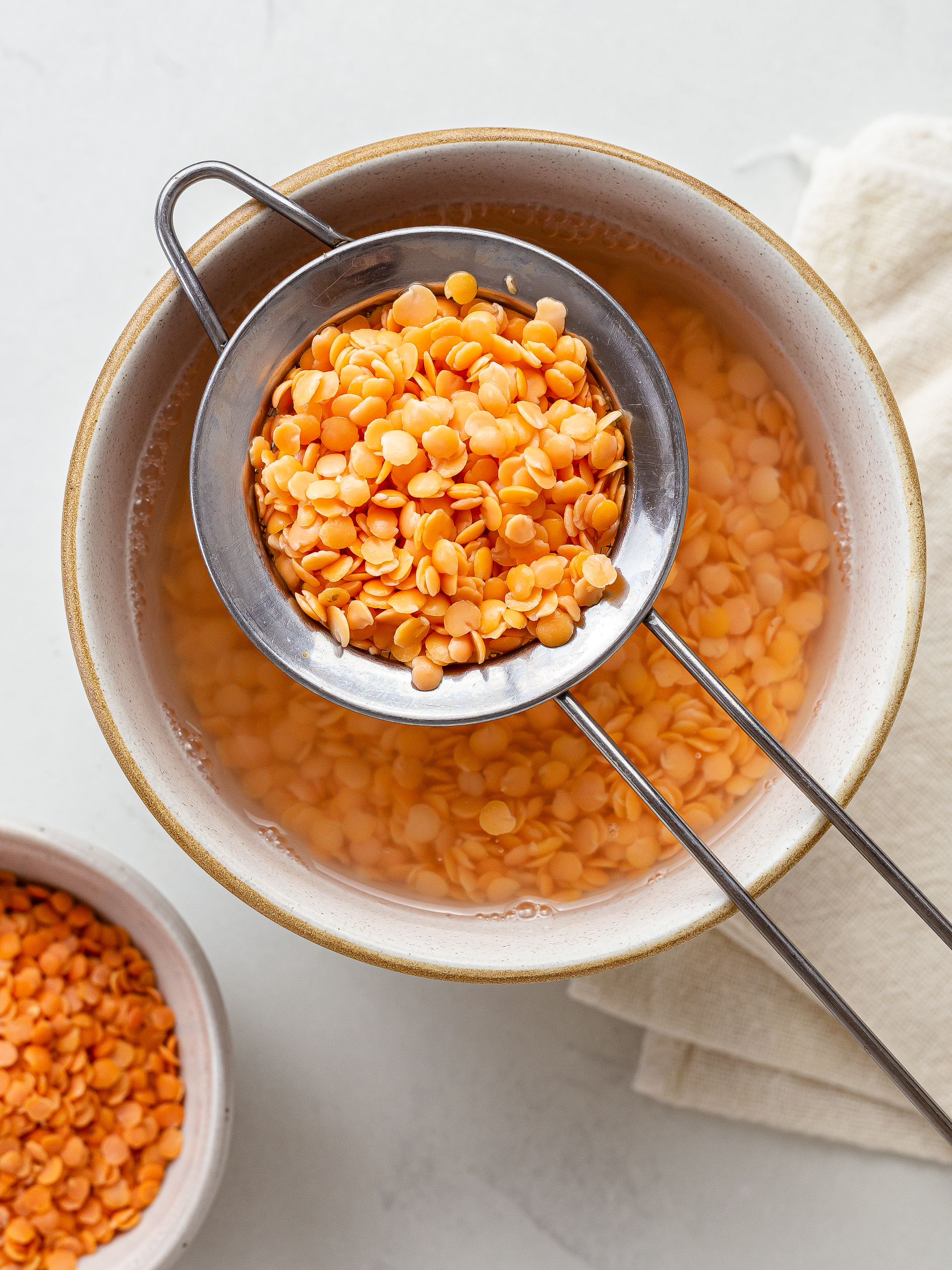 dry red lentils soaking in a bowl of water