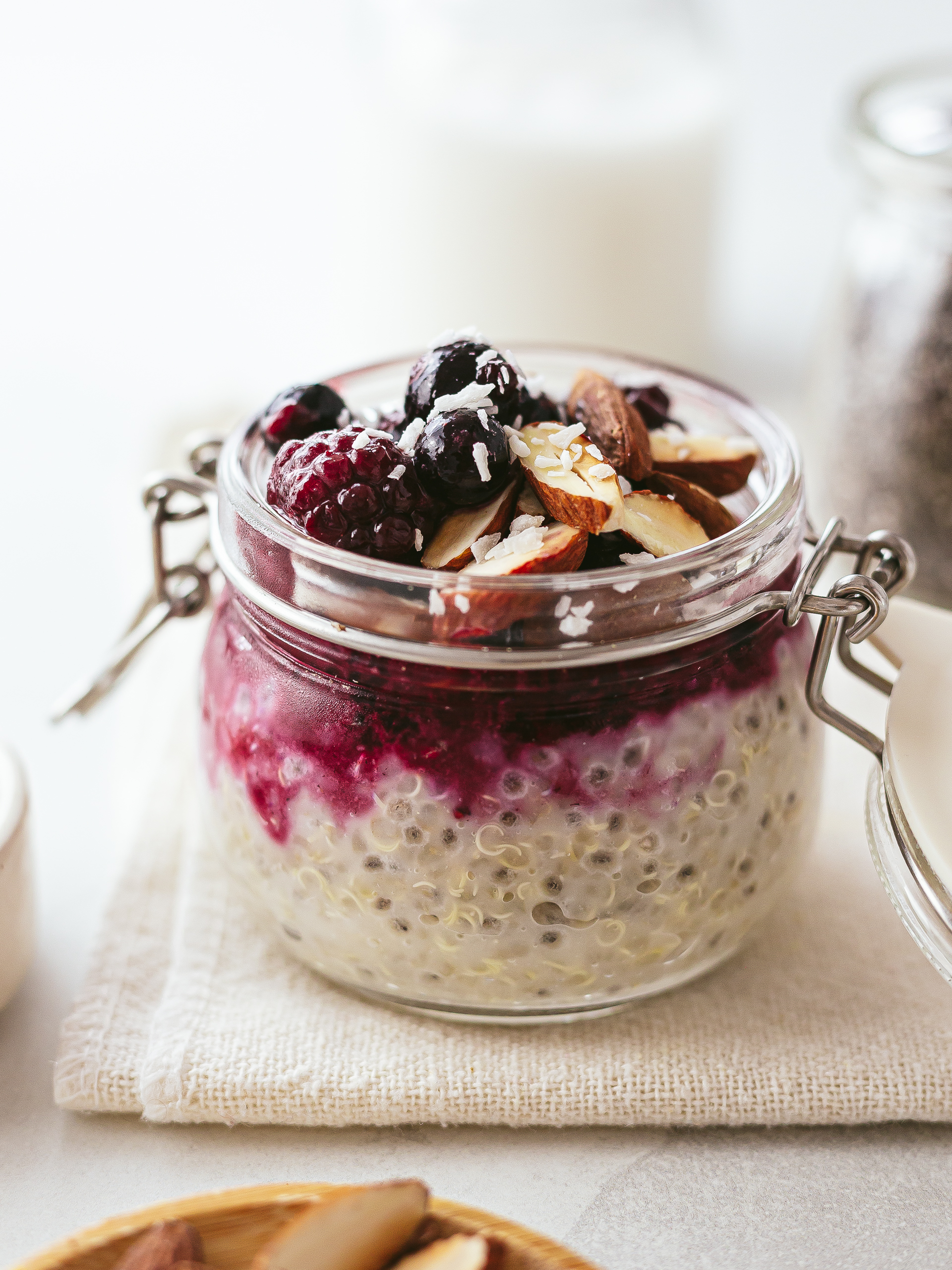 chia quinoa pudding in a jar with berries and almonds topping