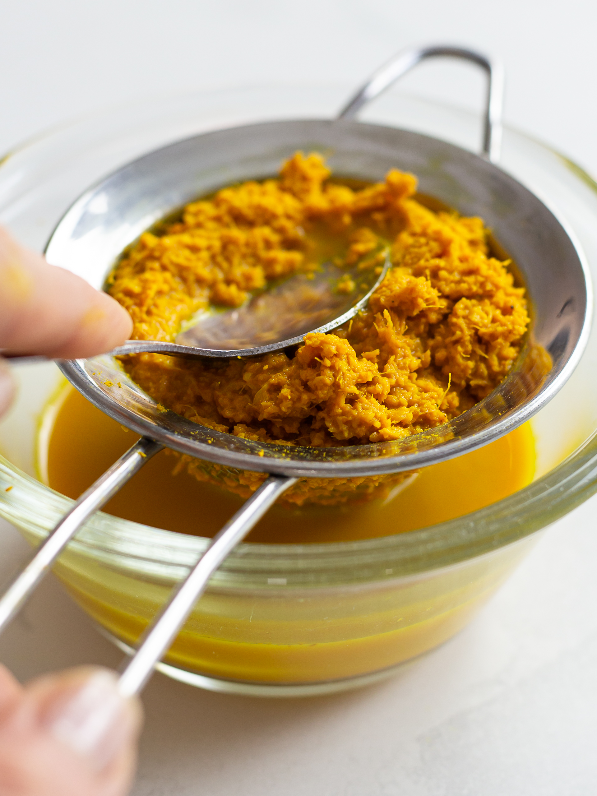 Ginger turmeric paste is strained through a strainer to remove water