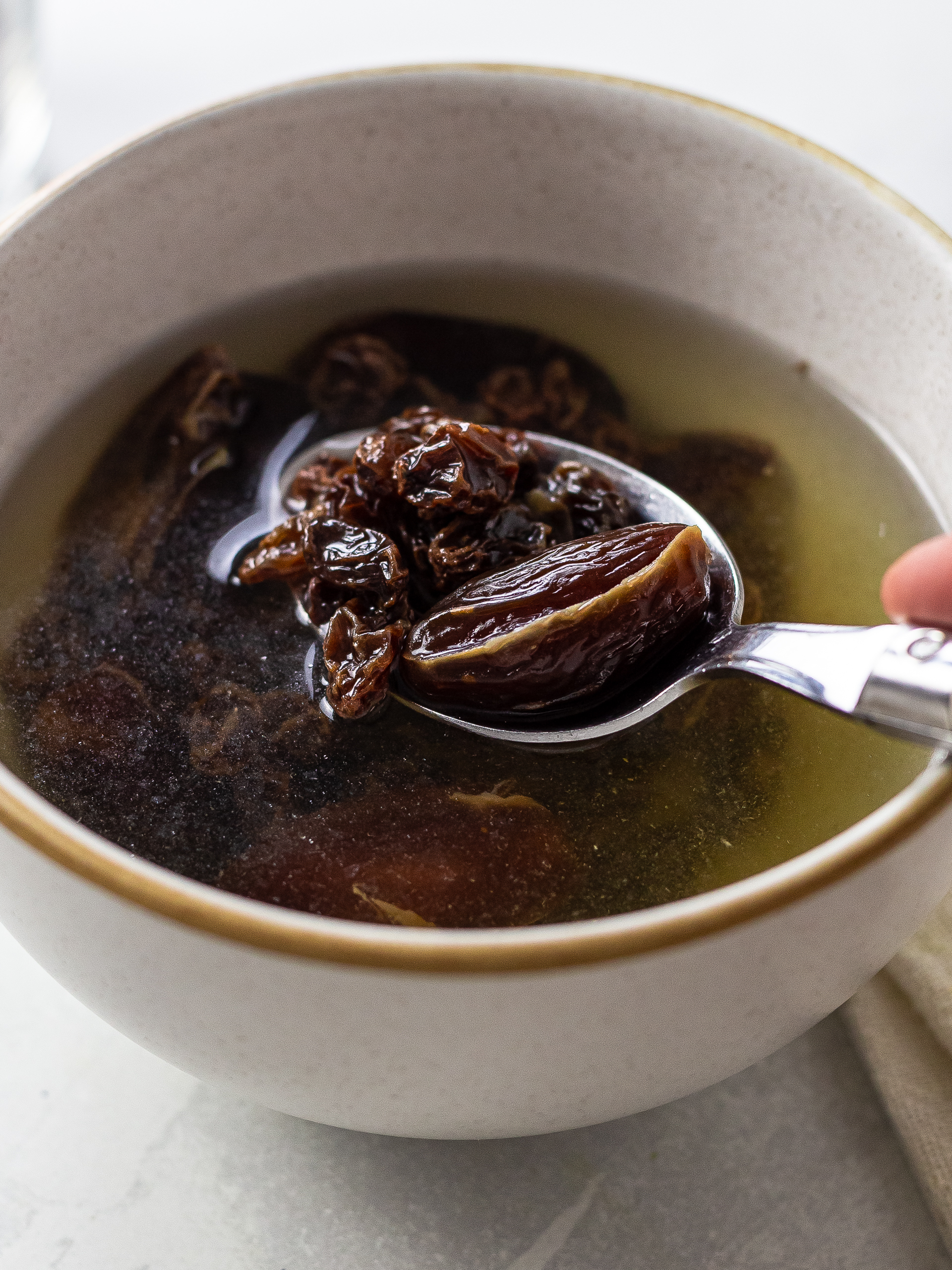 dates and raisins soaking in a bowl of hot water