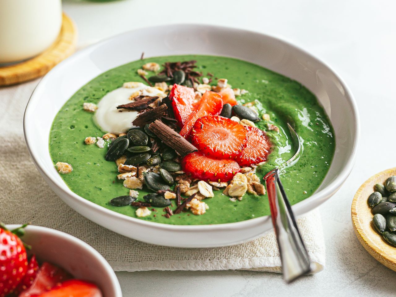 green spinach smoothie bowl with strawberries chocolate and oats