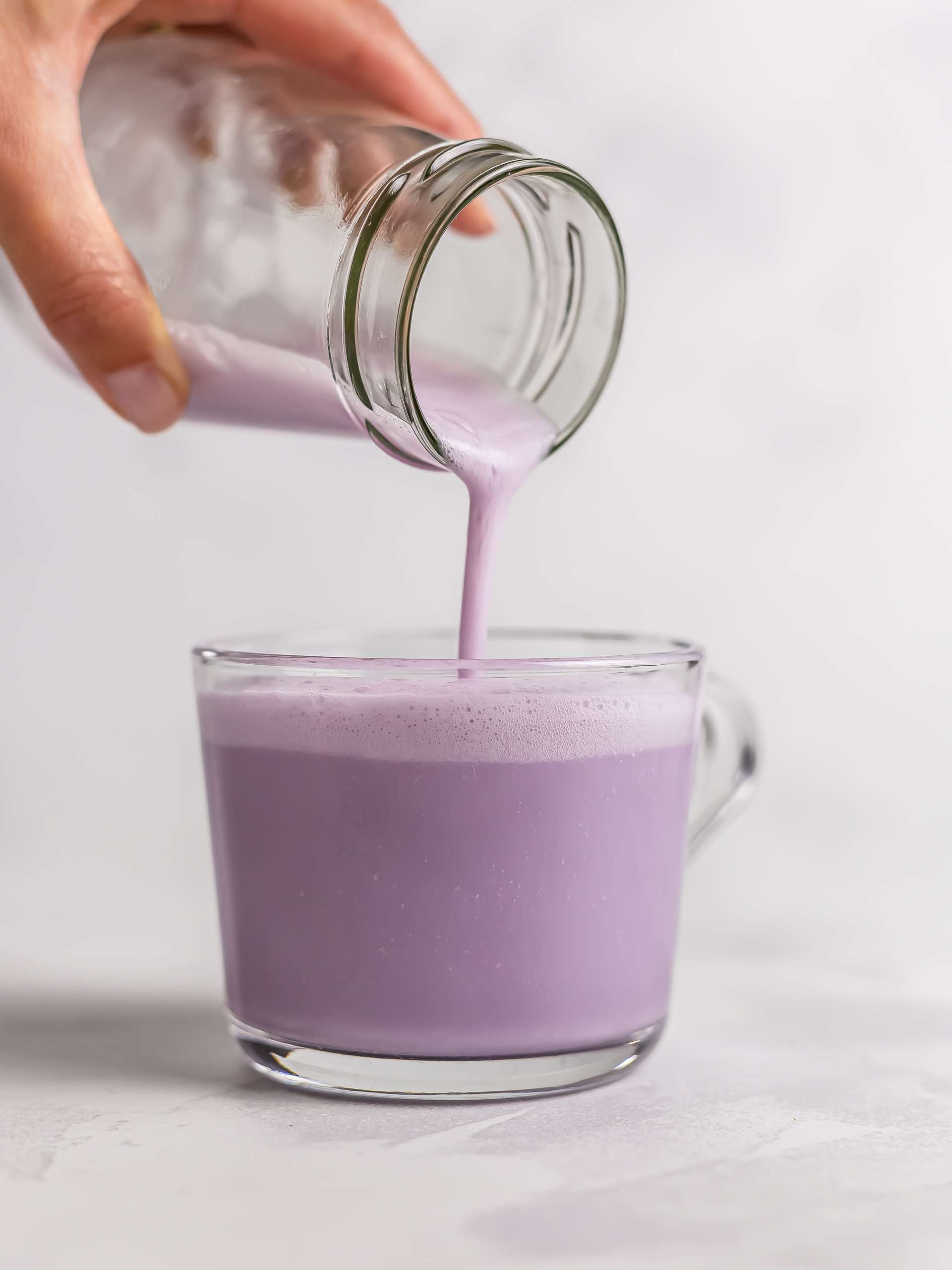 pouring ube latte into a cup