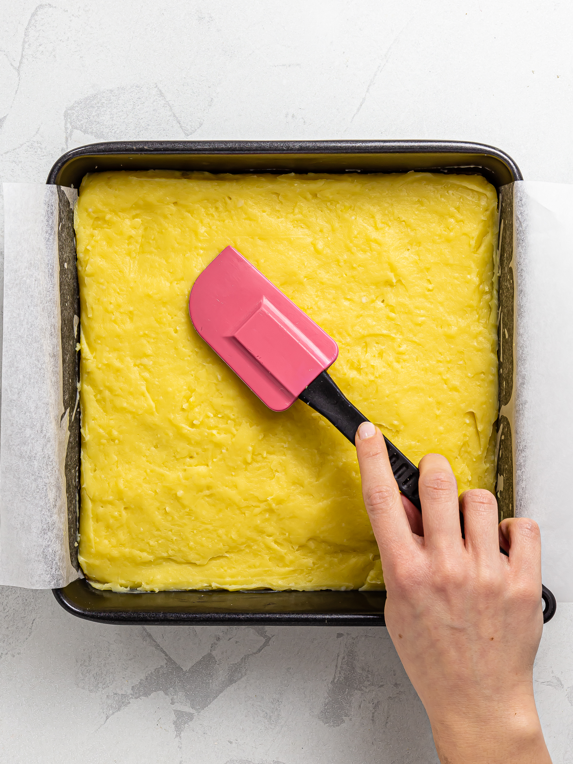 passion fruit custard spread over granola base slab in a tin