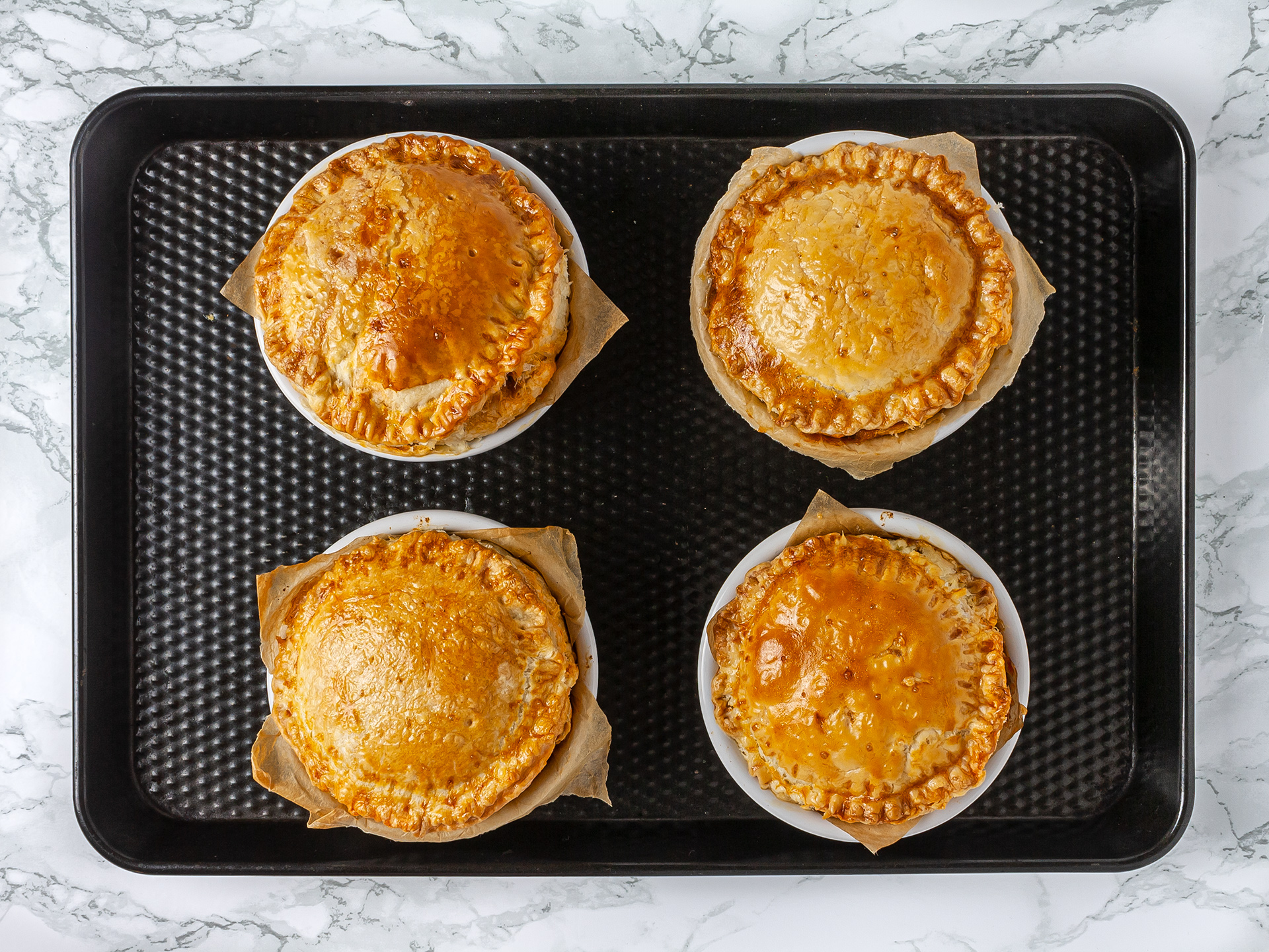 Single portion mince lamb pies baked in the oven on a tray