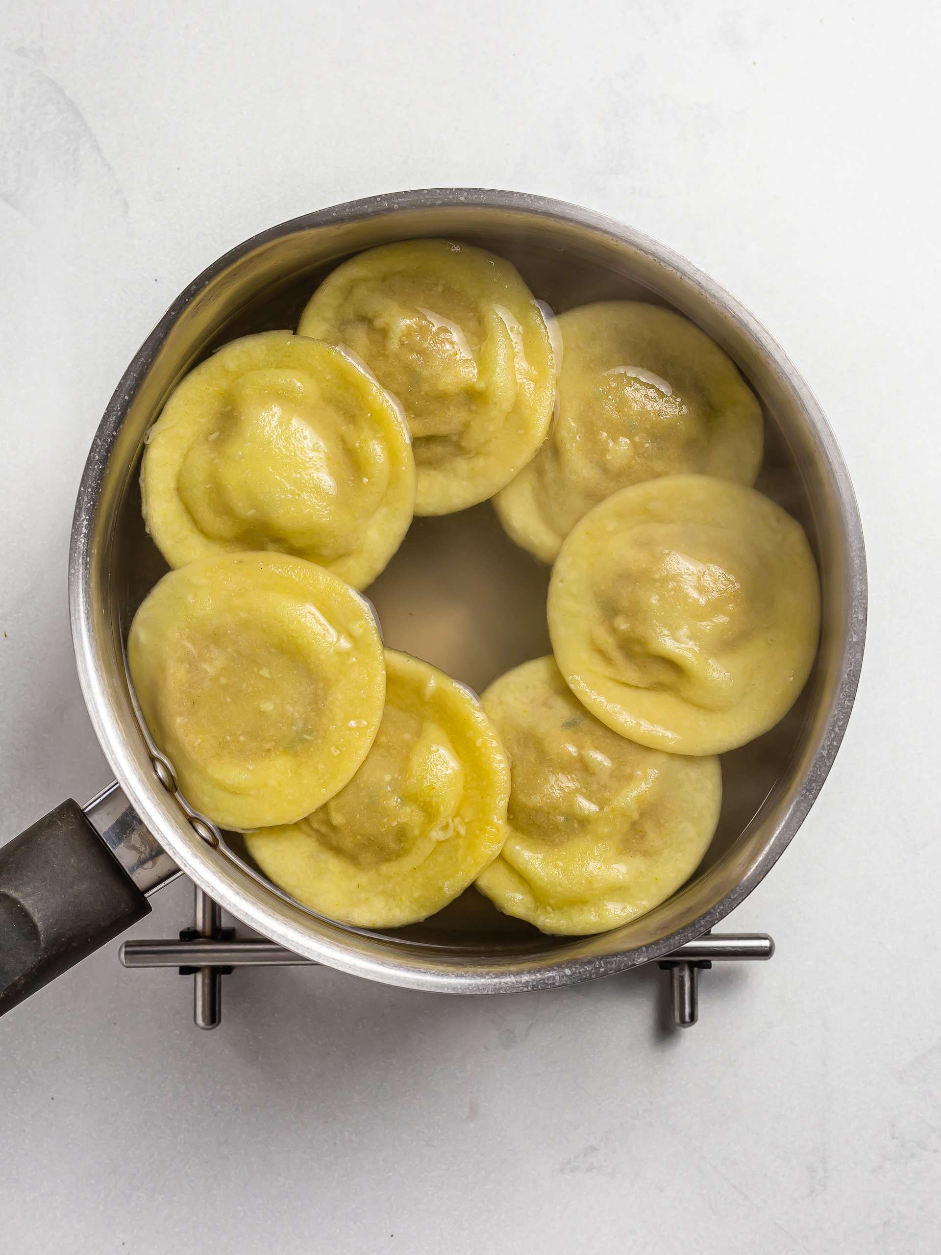 cooked ravioli floating in a pot of water