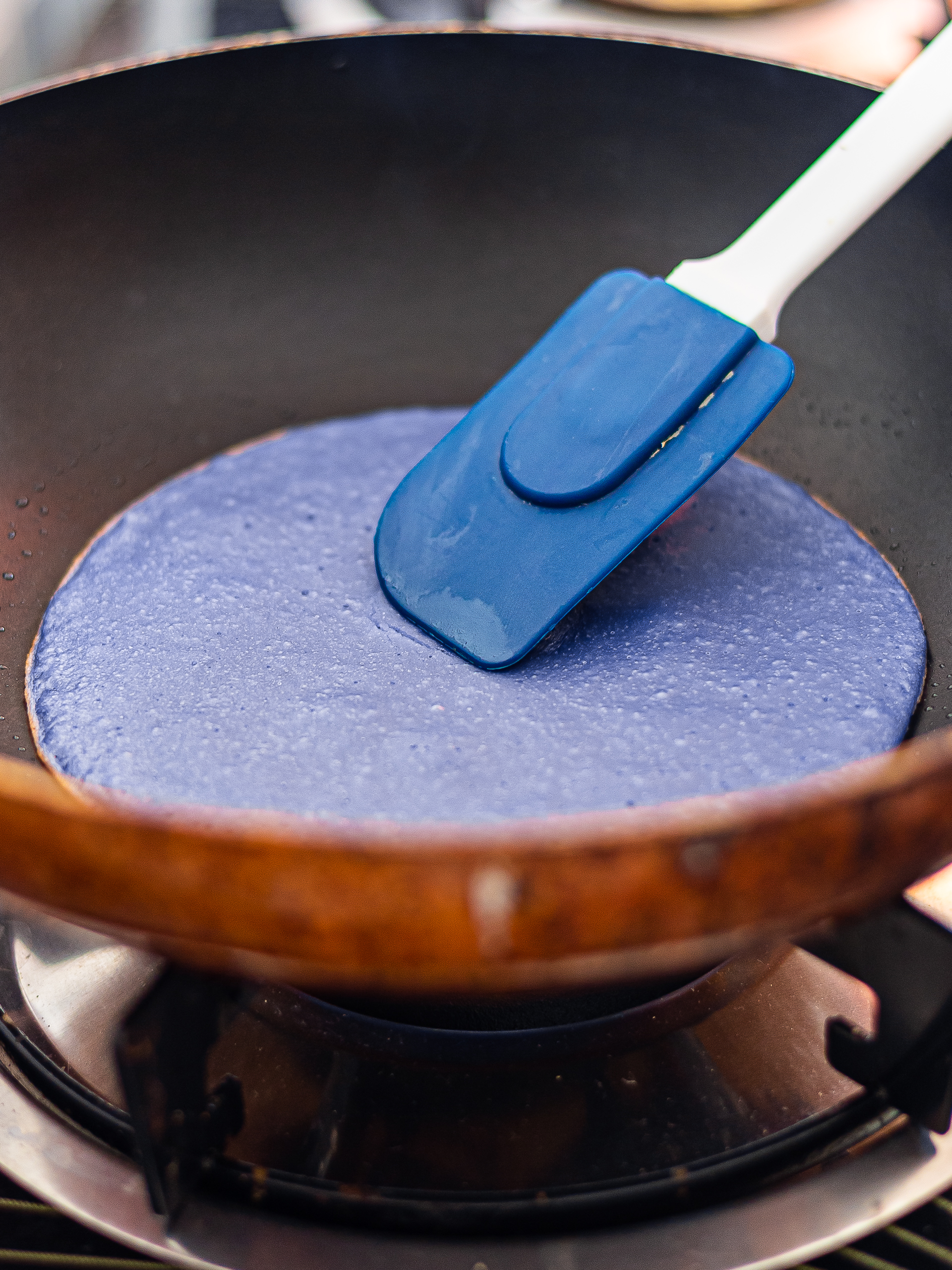 blue crepe pancake cooking in a skillet