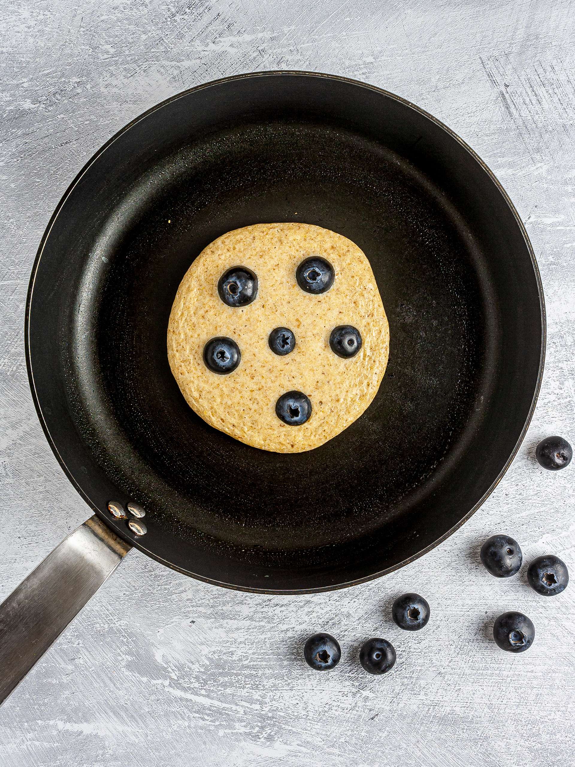 Pancake with blueberries cooking in a pan