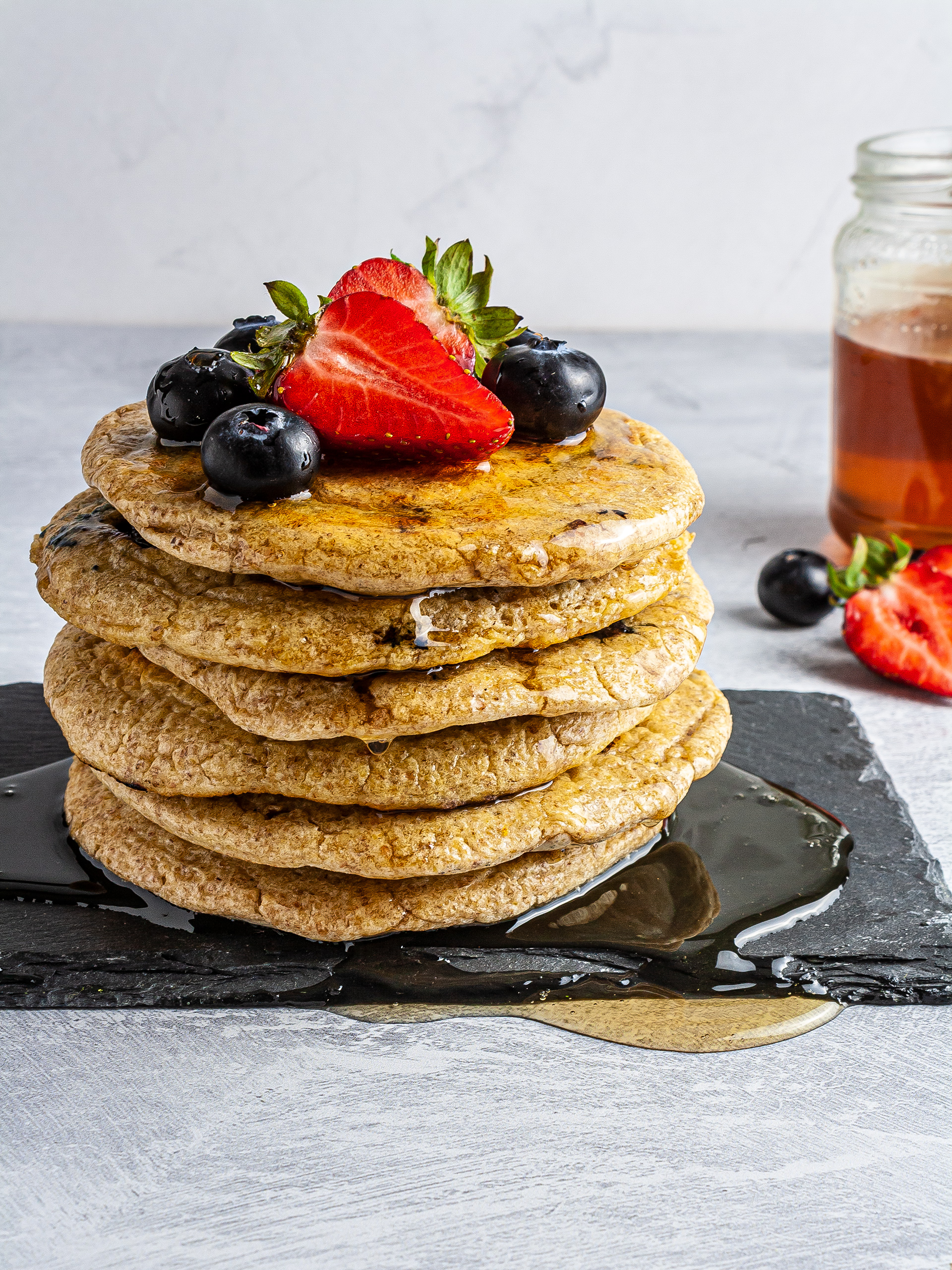 Stacked oatmeal pancakes with blueberries and strawberries