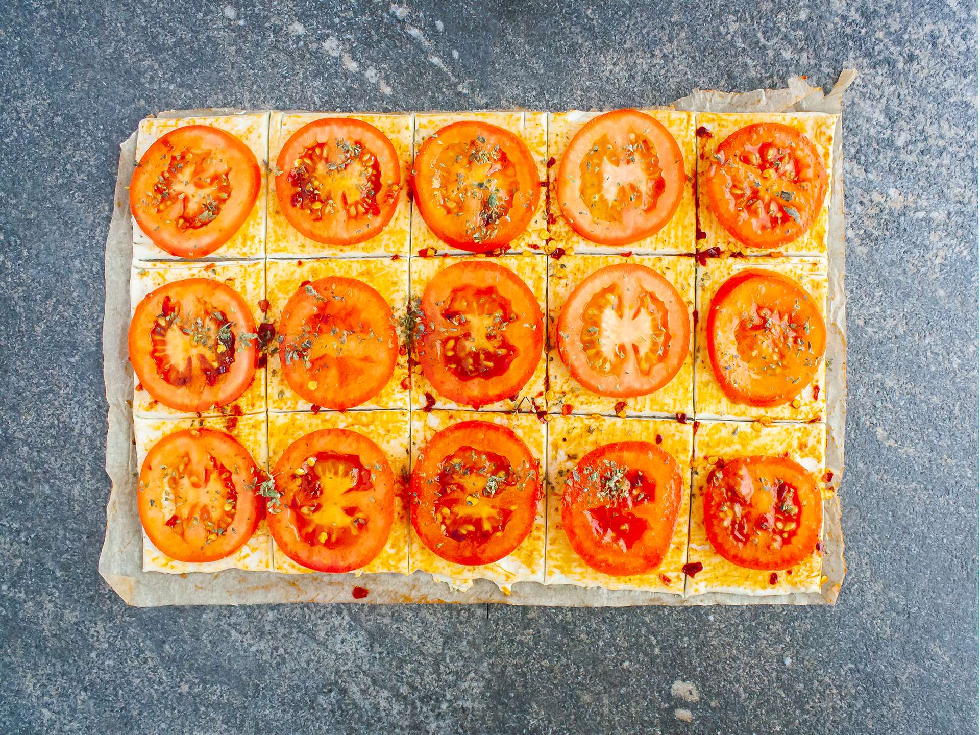 pastry sheet cut and  covered with tomato slices 