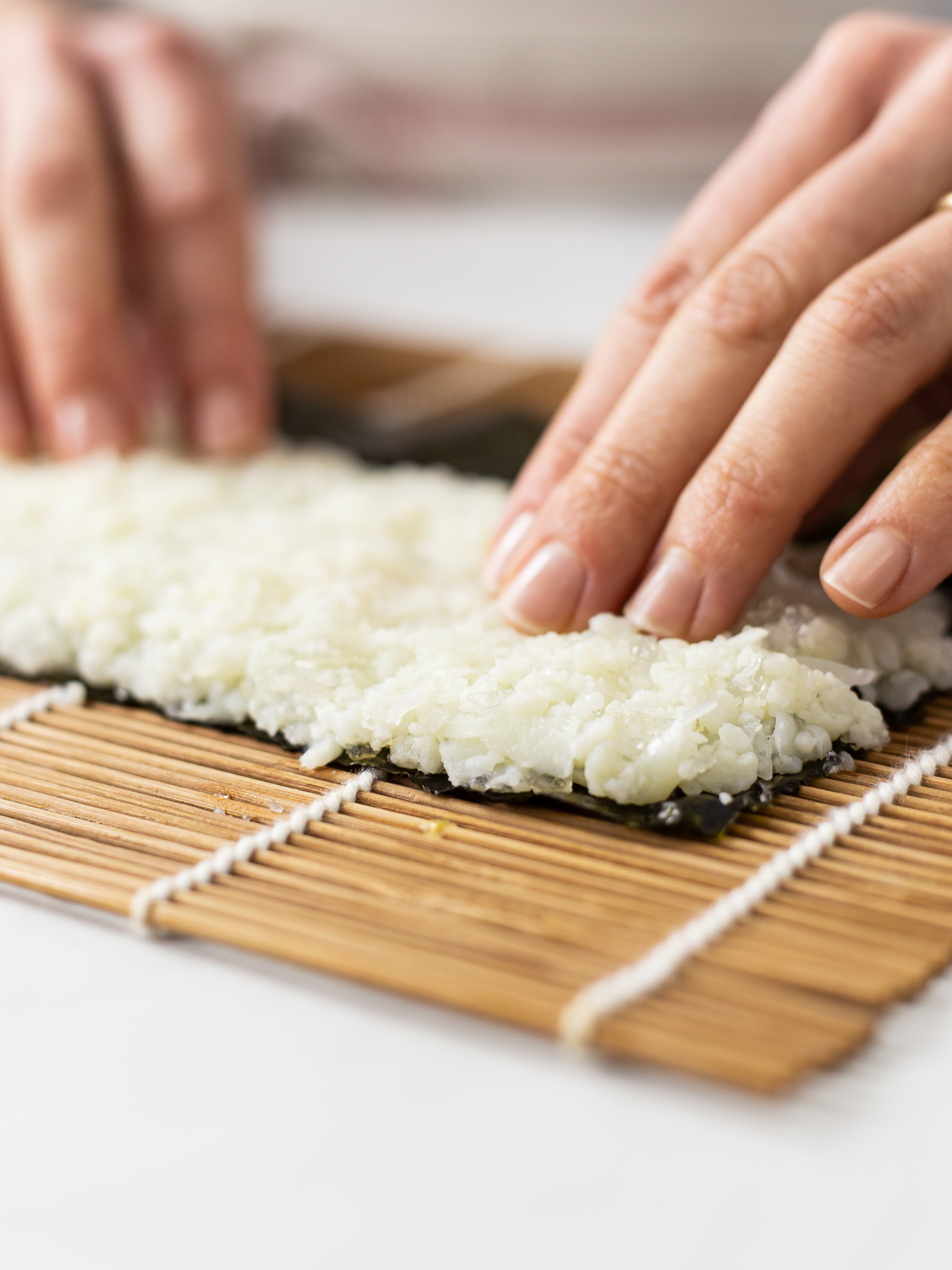 sticky cauliflower sushi rice on a nori sheet and bamboo mat