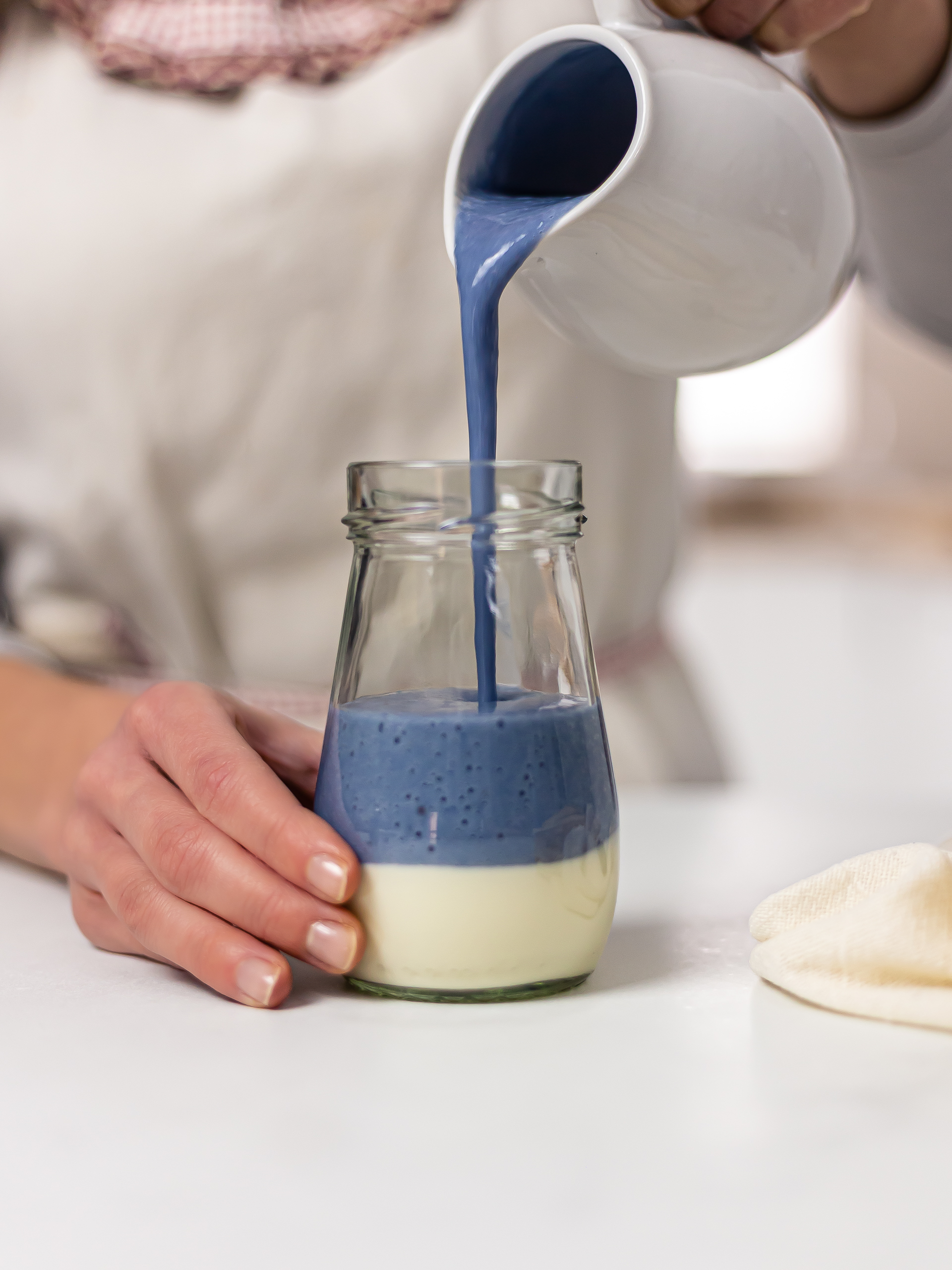 woman pouring butterfly pea smoothie in a jar with yogurt