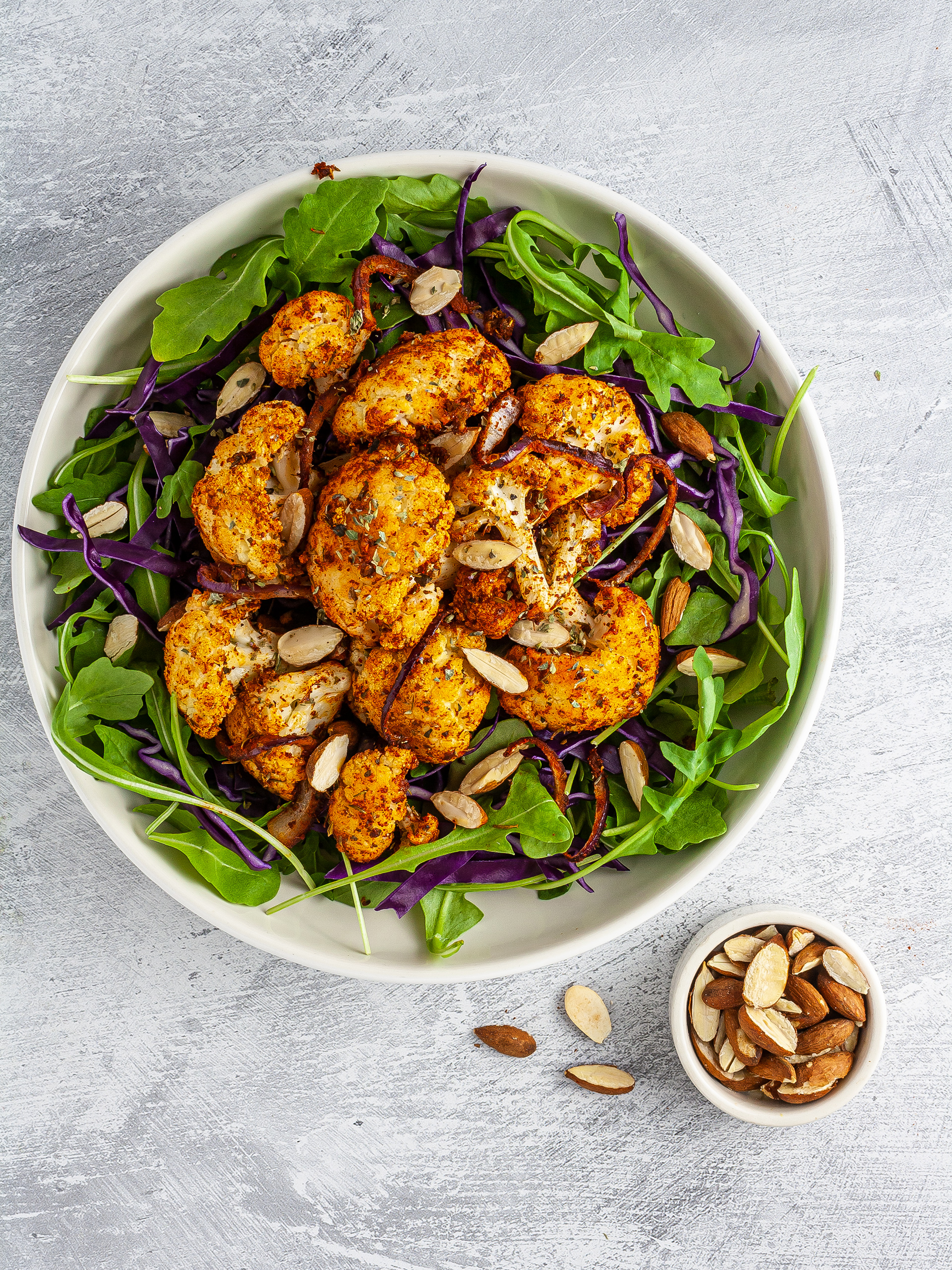 Salad topped with cajun cauliflowers and toasted almonds.