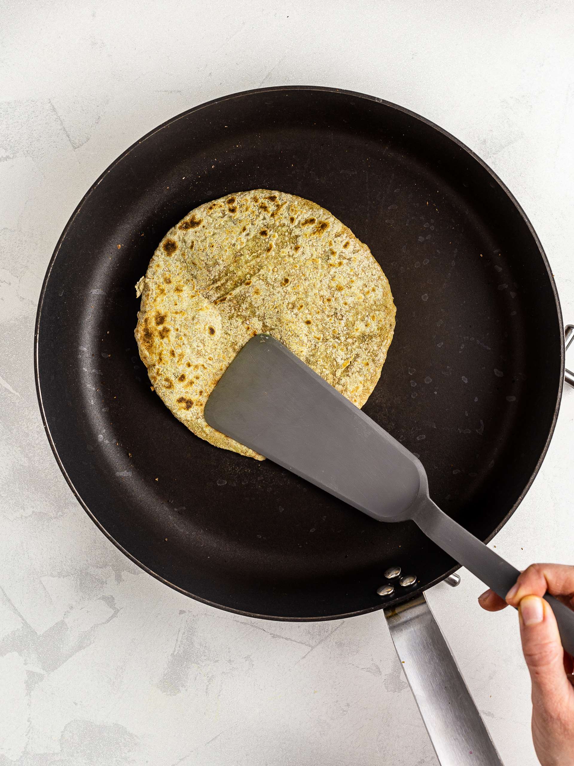 cooking avocado chapati in a skillet