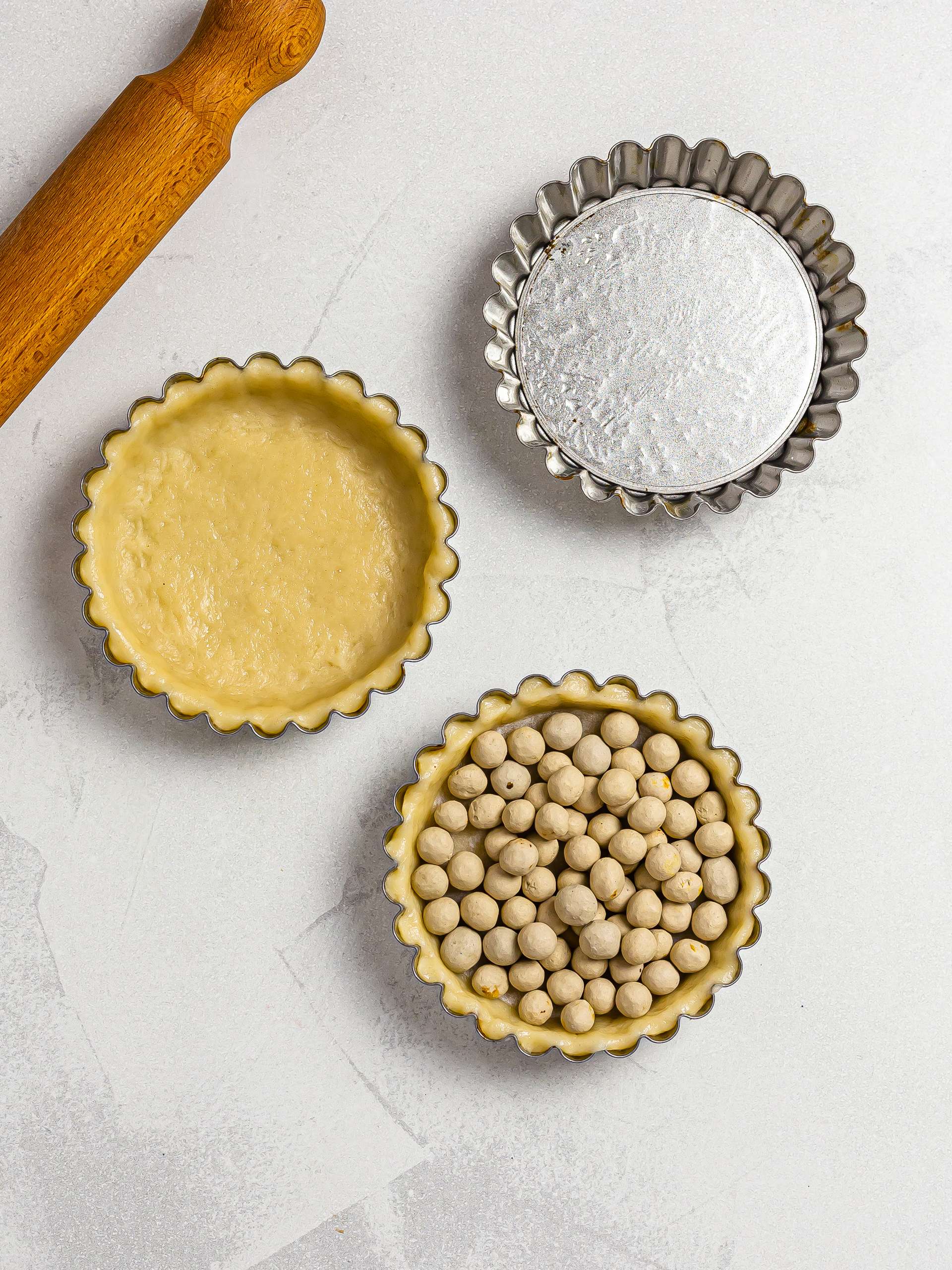 tart tins with pastry dough and baking beads for mont blanc tarts