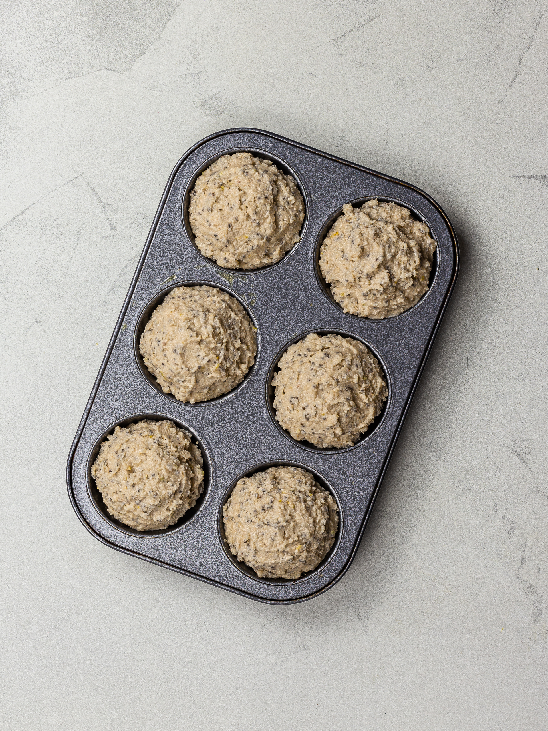 lemon chia seed muffin batter in a muffin tin