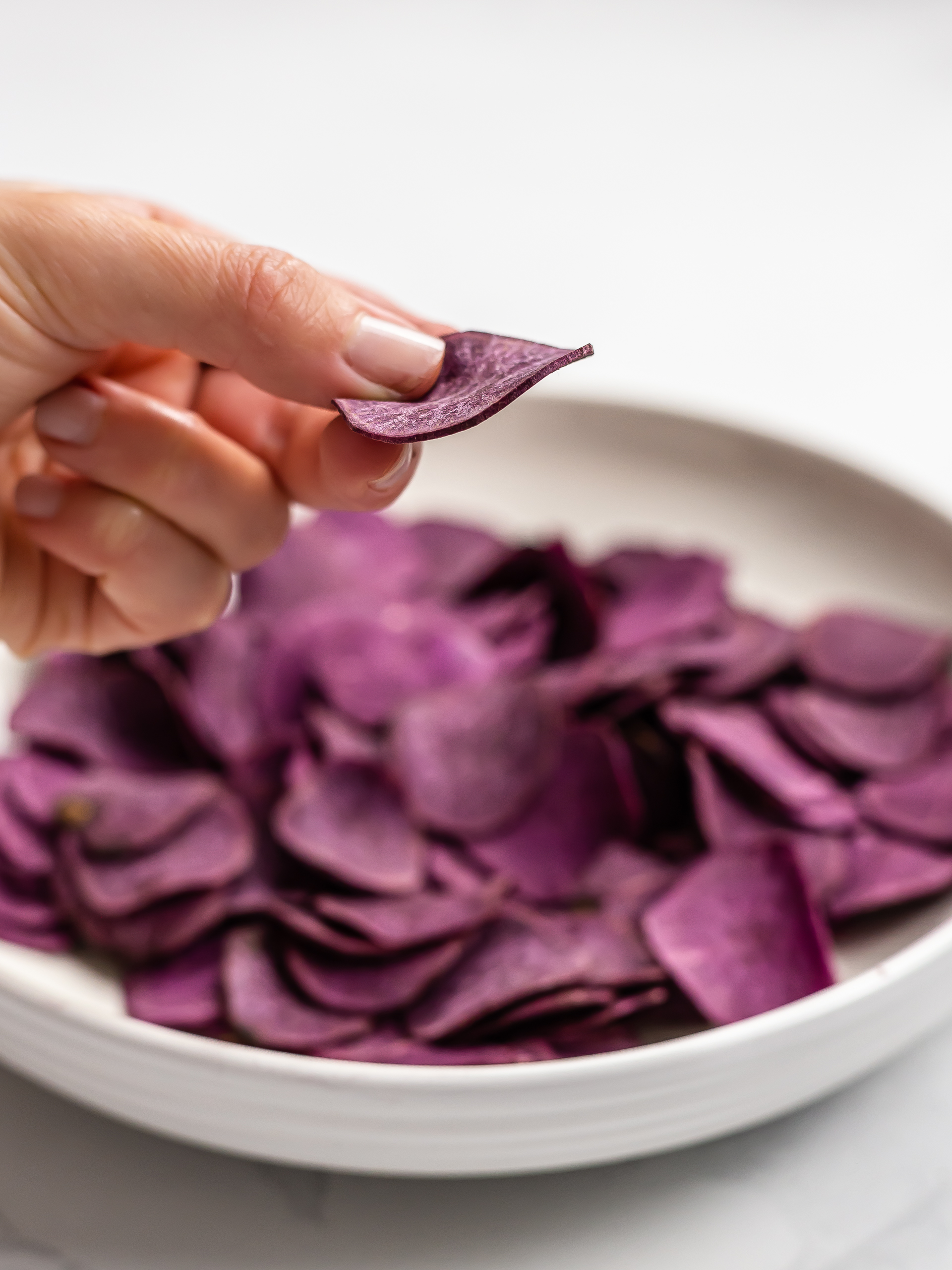 hand showing purple sweet potato chips thickness