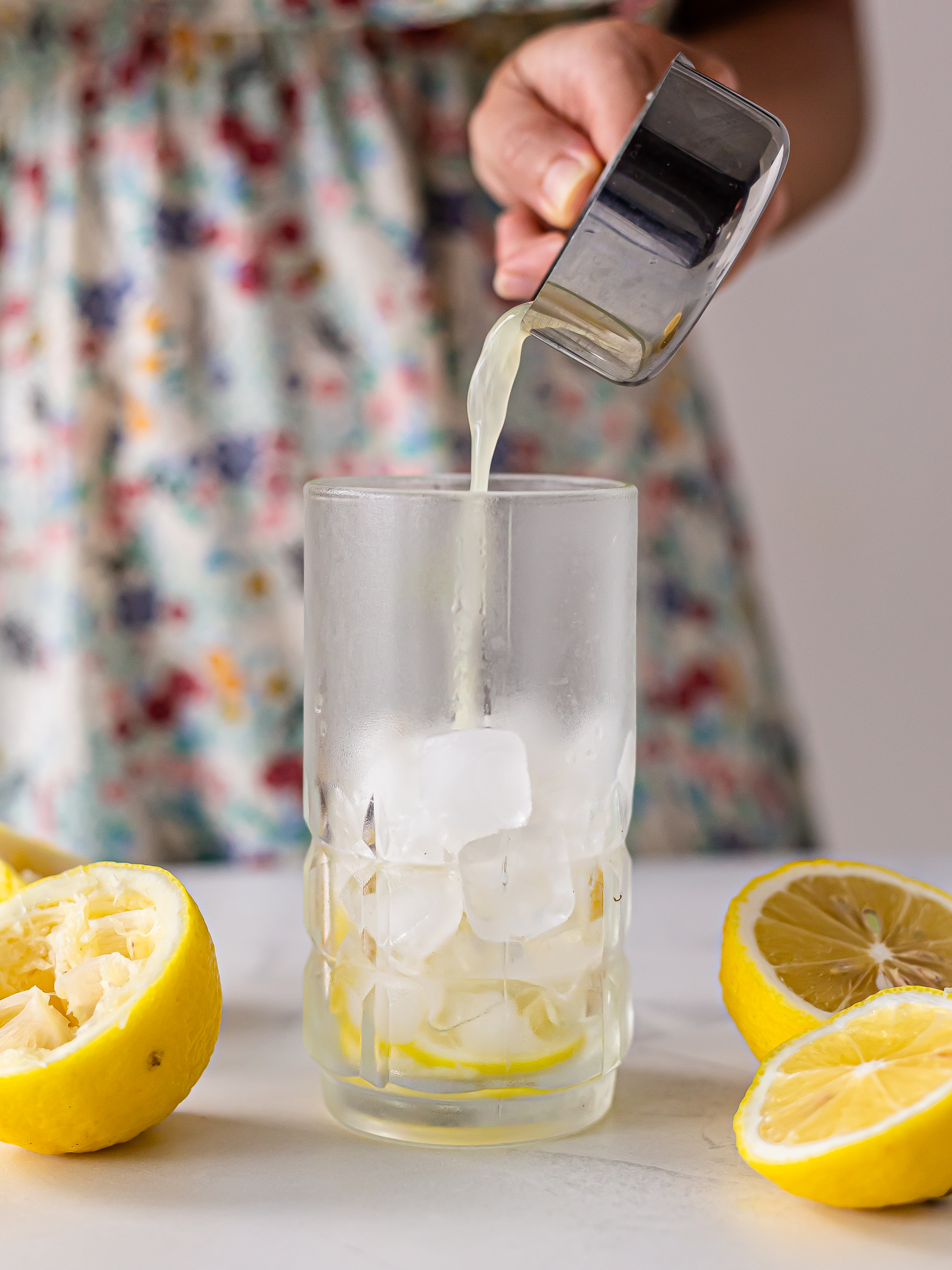 woman pouring lemon juice in a glass for lemonade