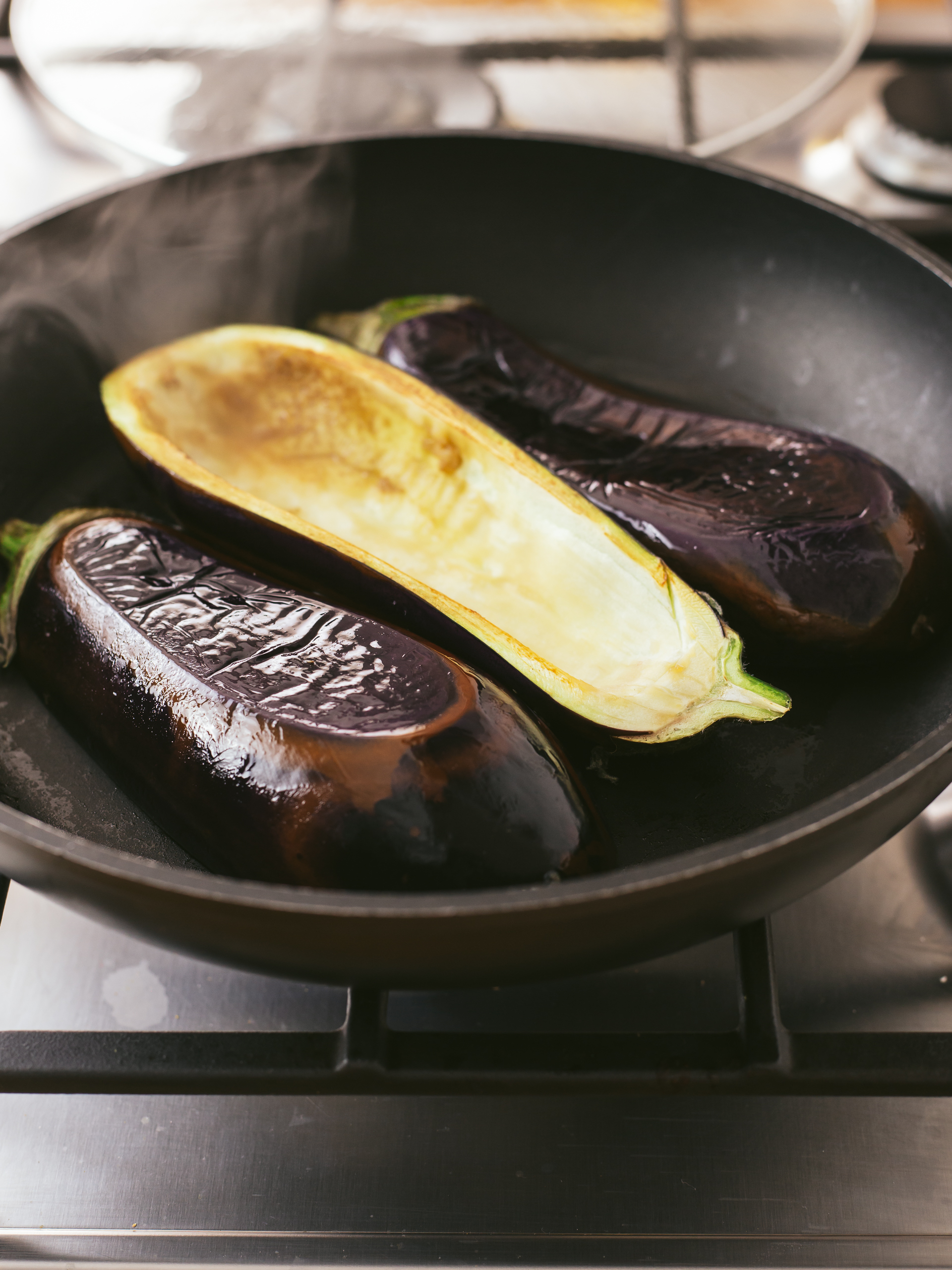 carved out eggplants cooking a pan