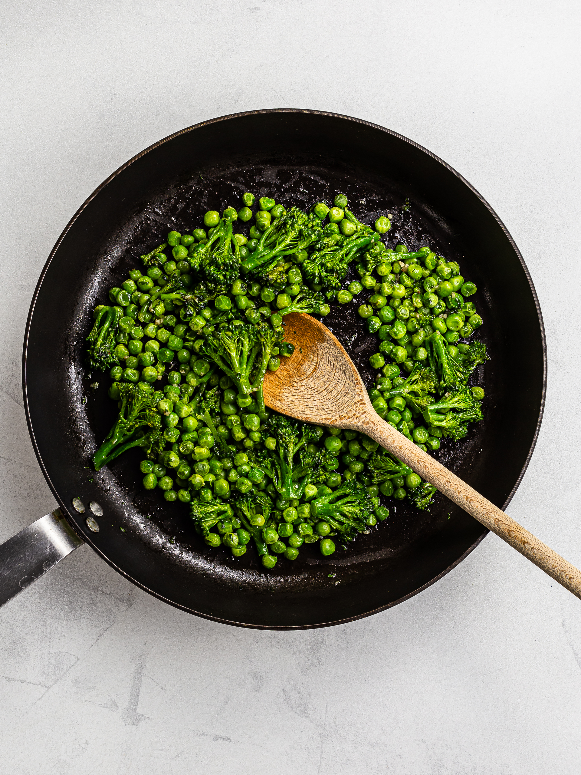 peas and broccoli cooked in a skillet with parsley