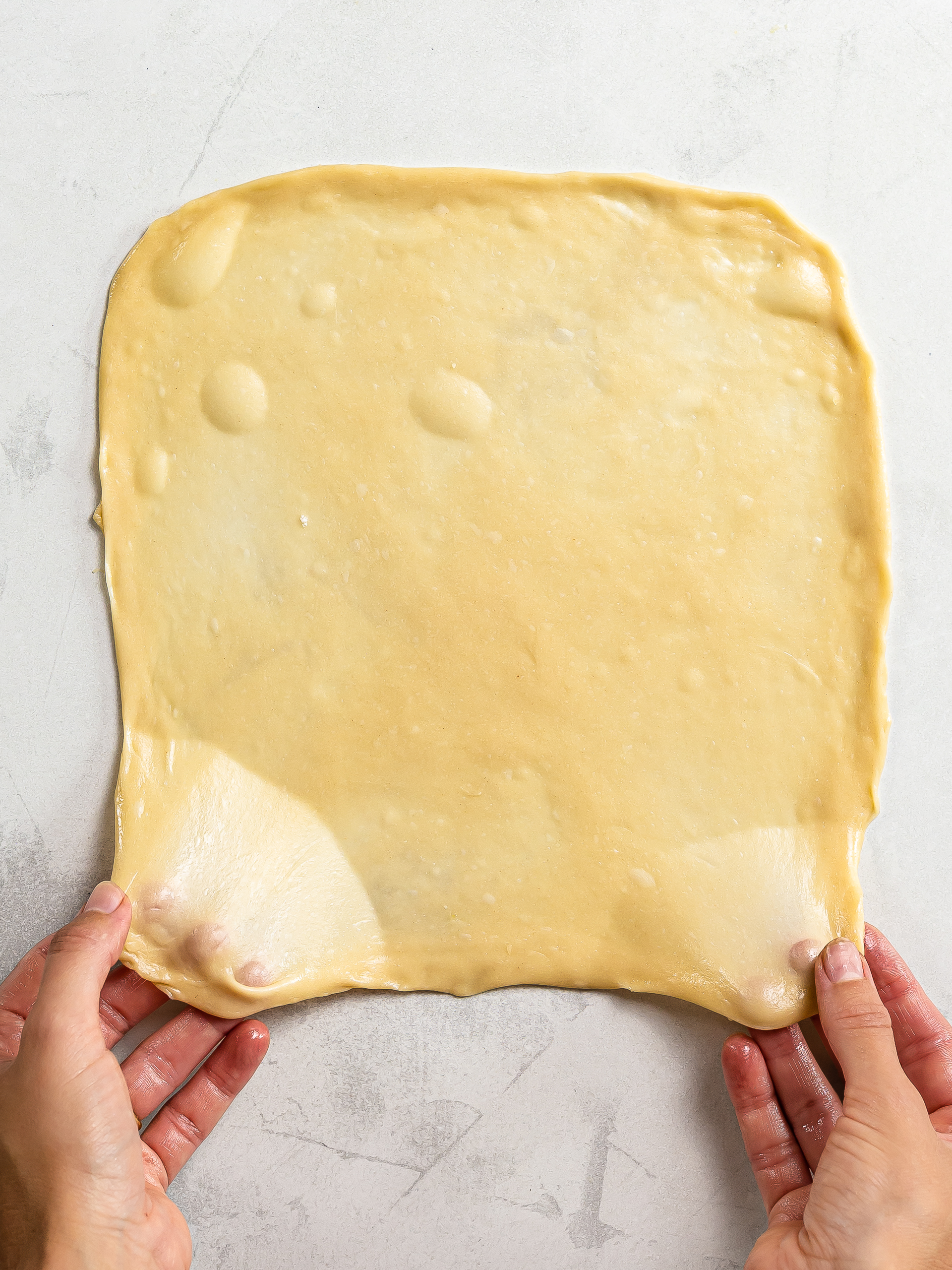 woman stretching dough into a thin pancake