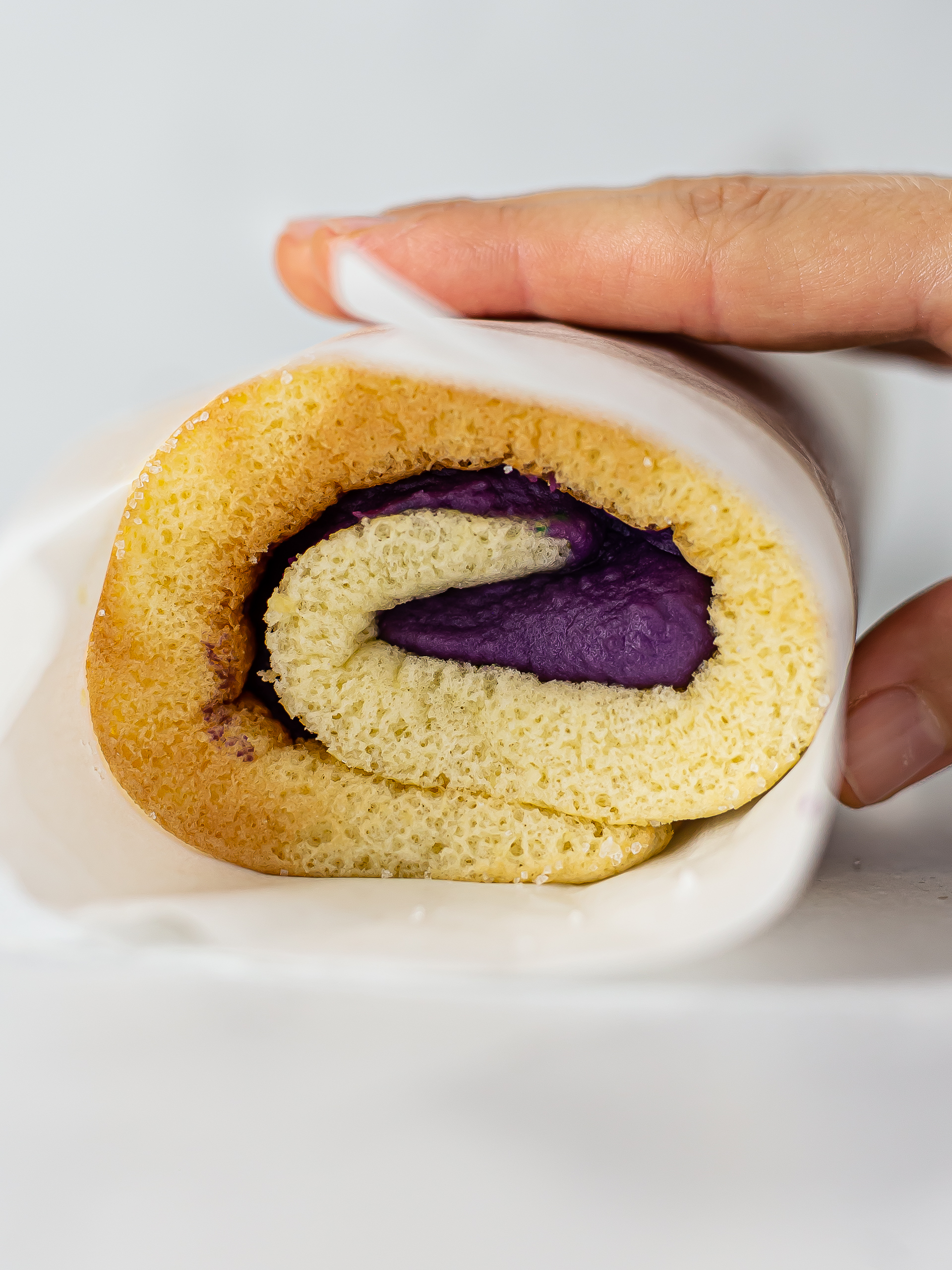 cake roll filled with ube butter wrapped in baking paper