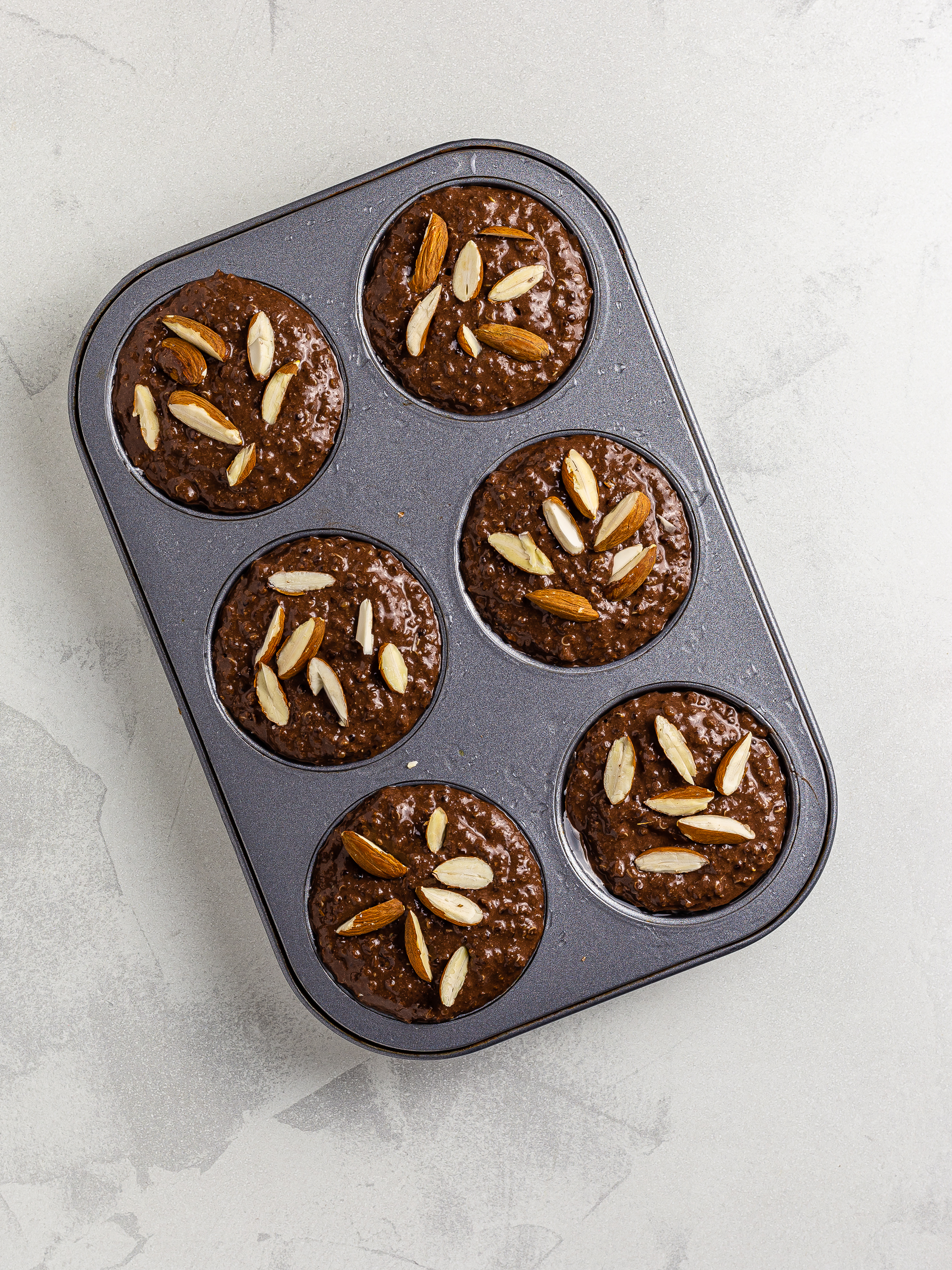 chocolate muffins in a muffin tin with almonds