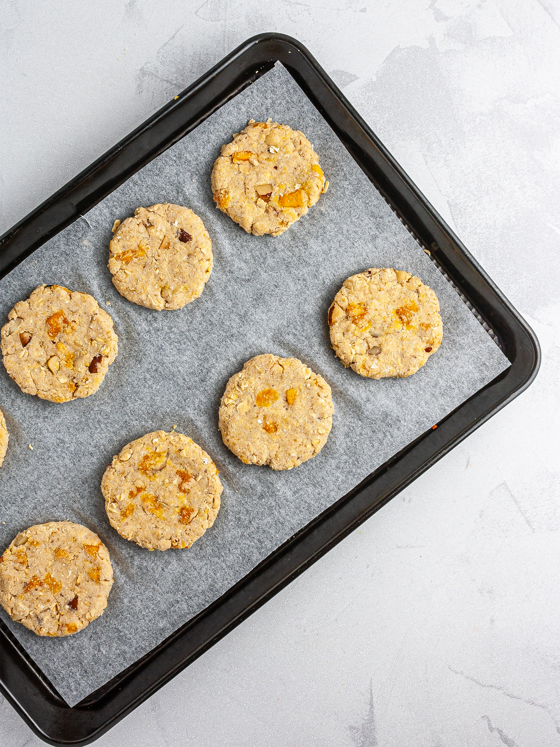 Dough shaped into cookies over a baking tray.