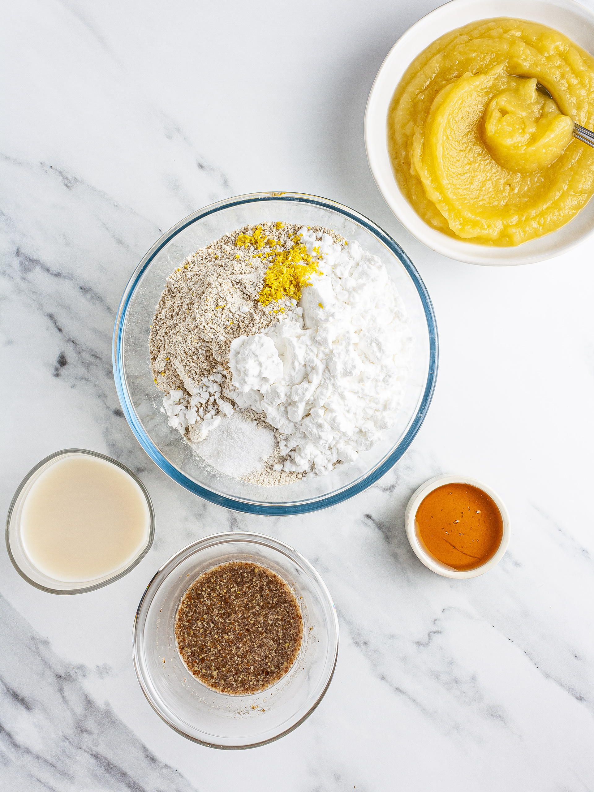 Buckwheat, oats, flaxseeds, milk, and applesauce in a mixing bowl