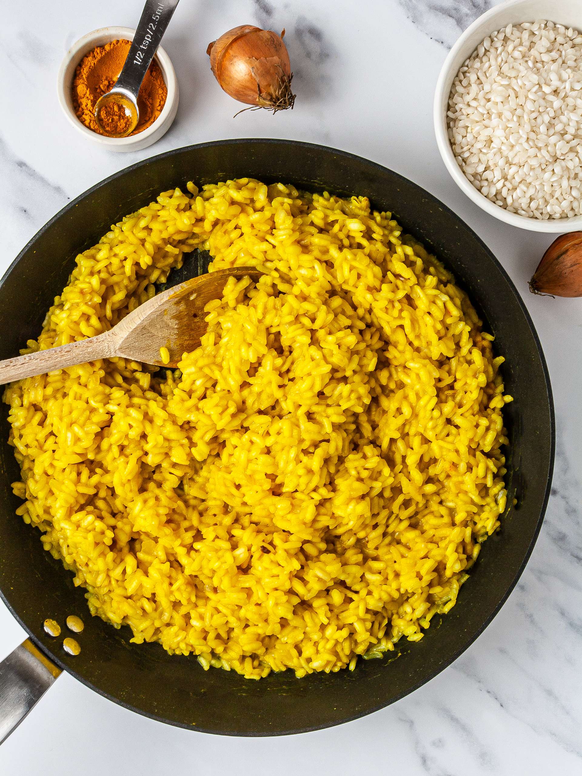 Risotto rice cooked in a pan with onions and turmeric.