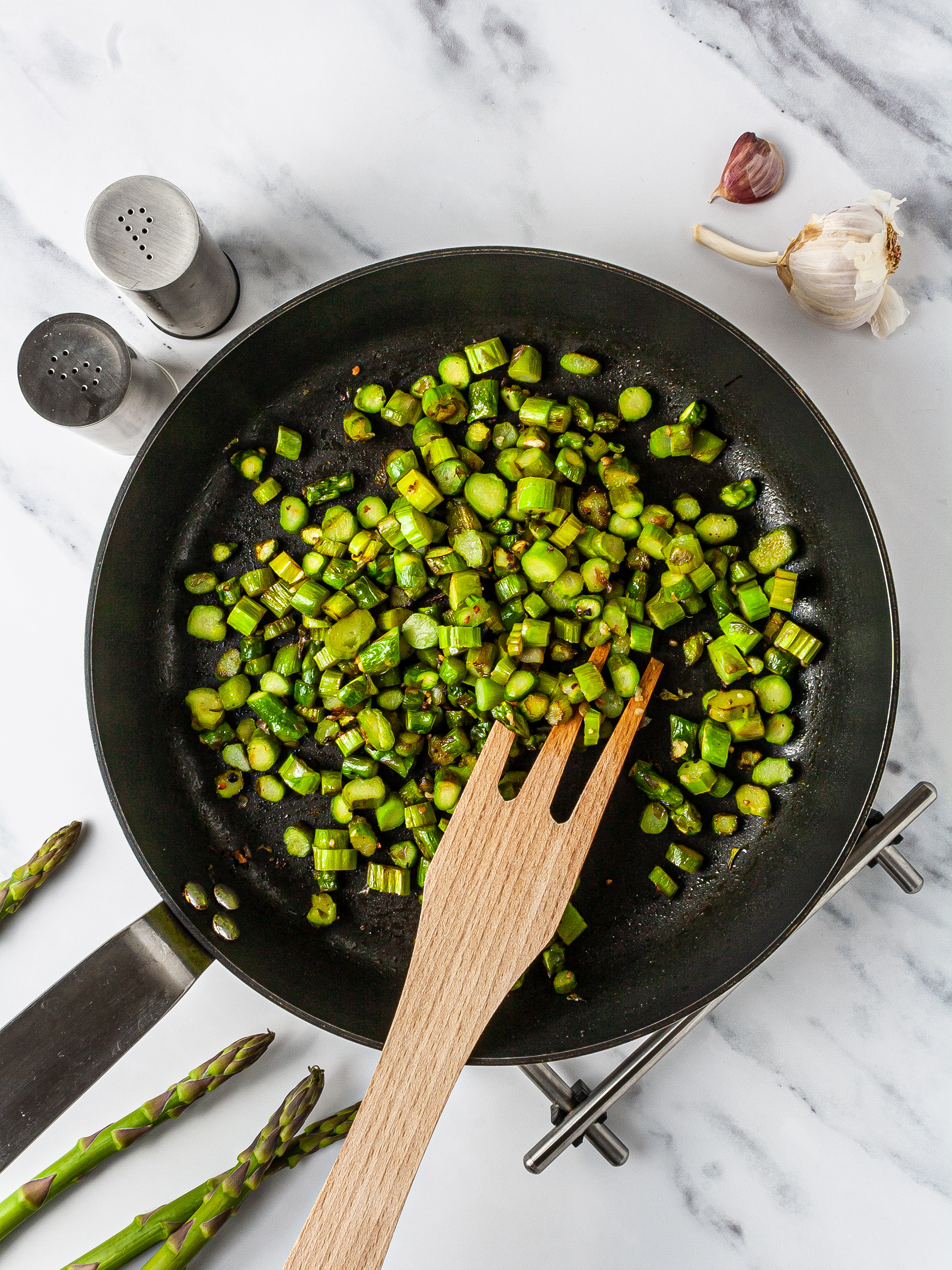 Asparagus cooking in a pan with garlic.