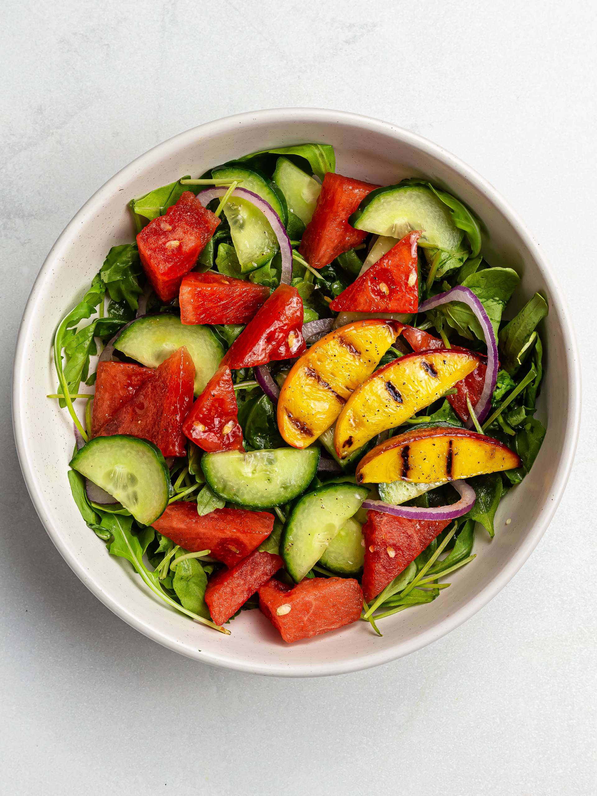 watermelon arugula salad with grilled peaches in a bowl