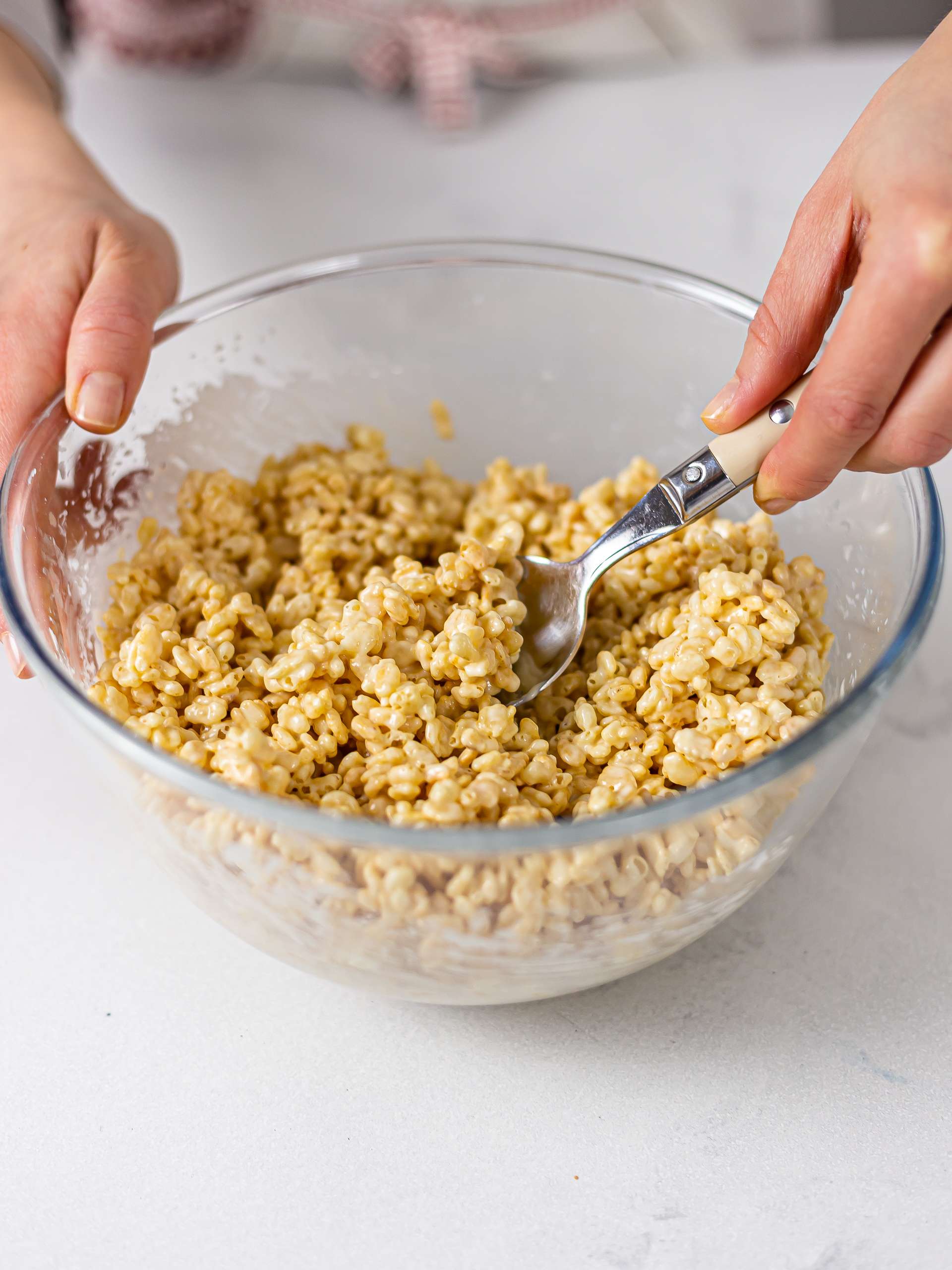woman mixing rice crispies with melted white chocolate