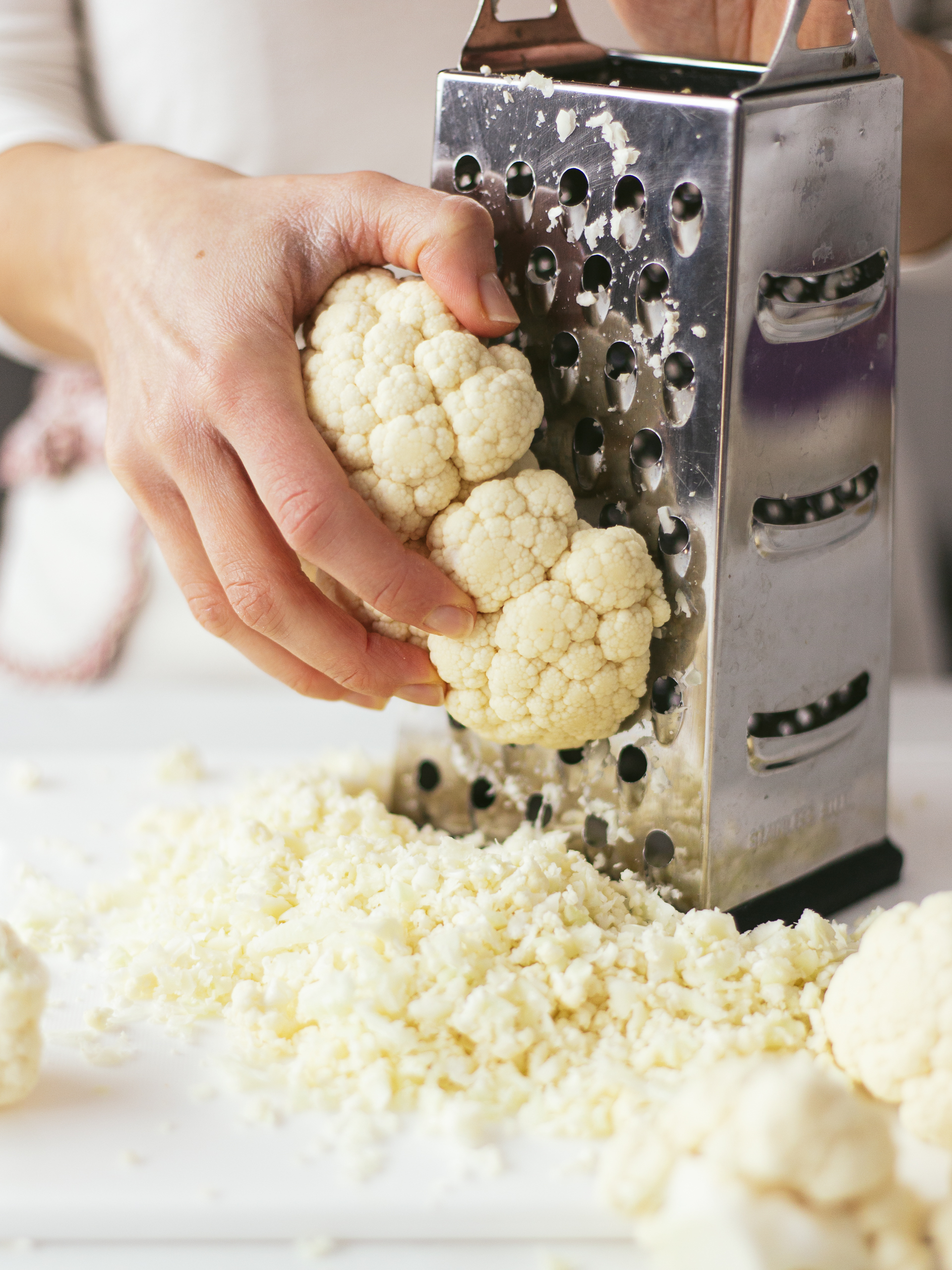 fresh cauliflower grated with a box grater for cauliflower rice
