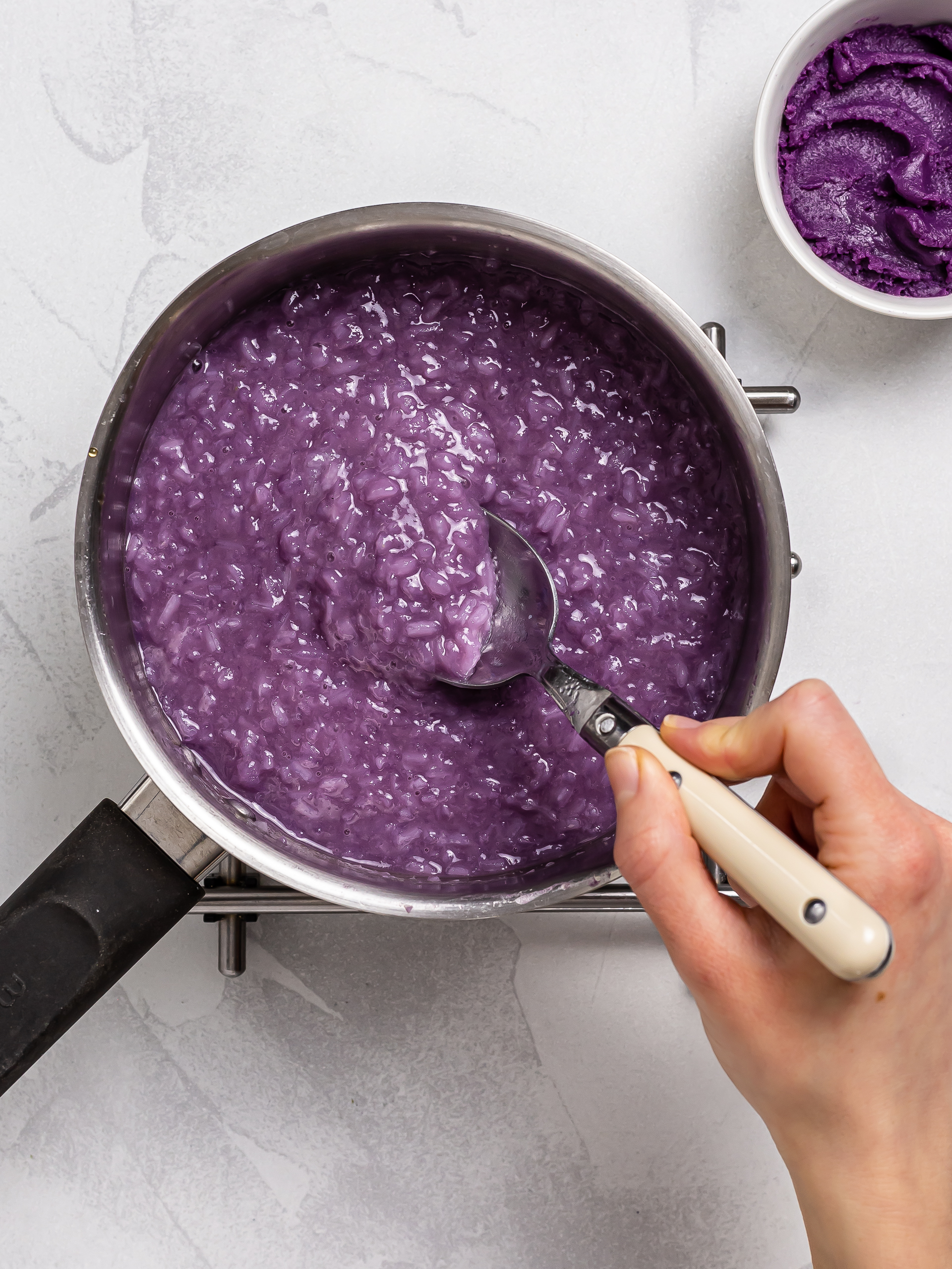 glutinous rice porridge cooking with ube halaya in a pot