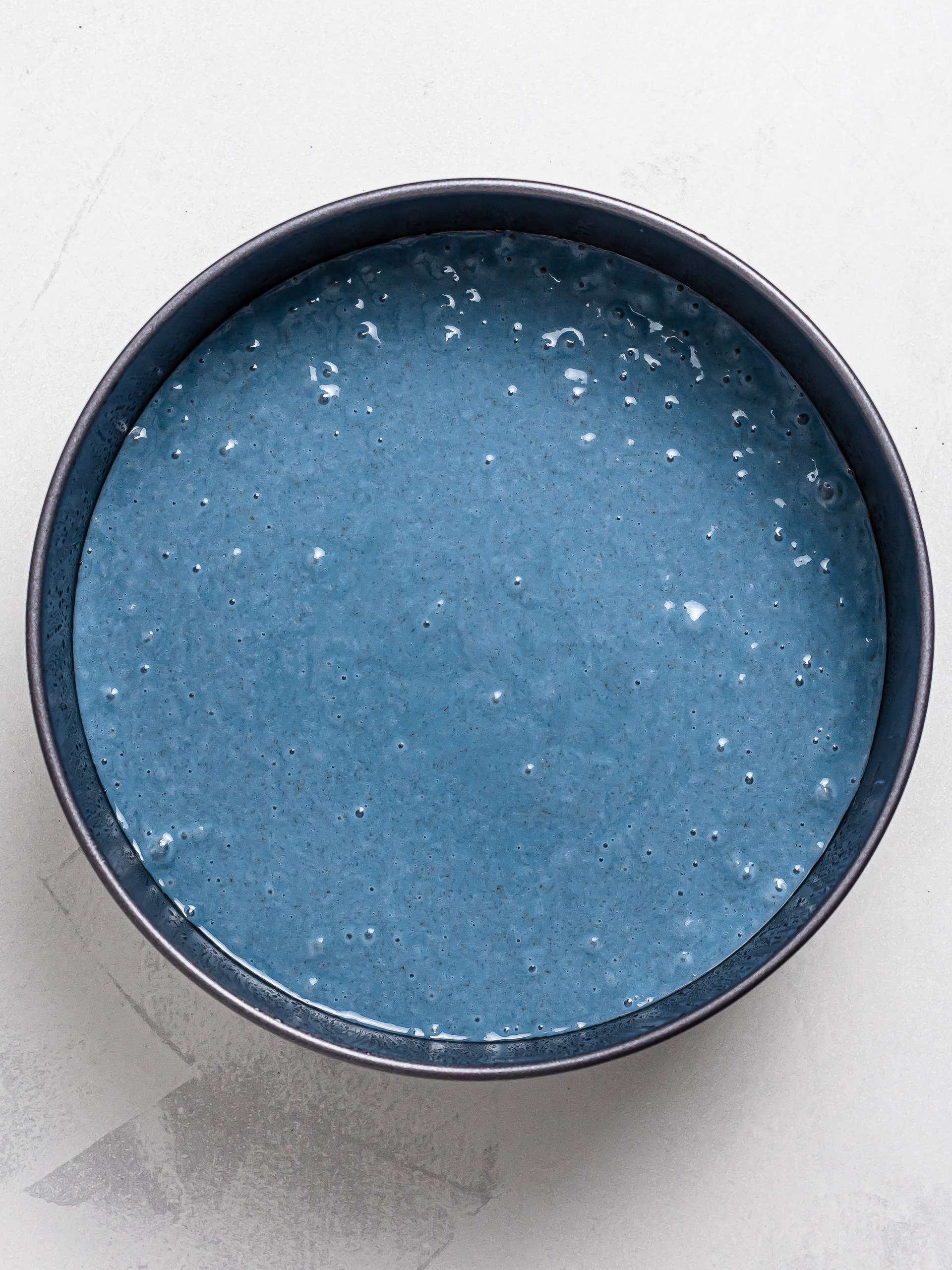 butterfly pea cake batter in a round cake tin