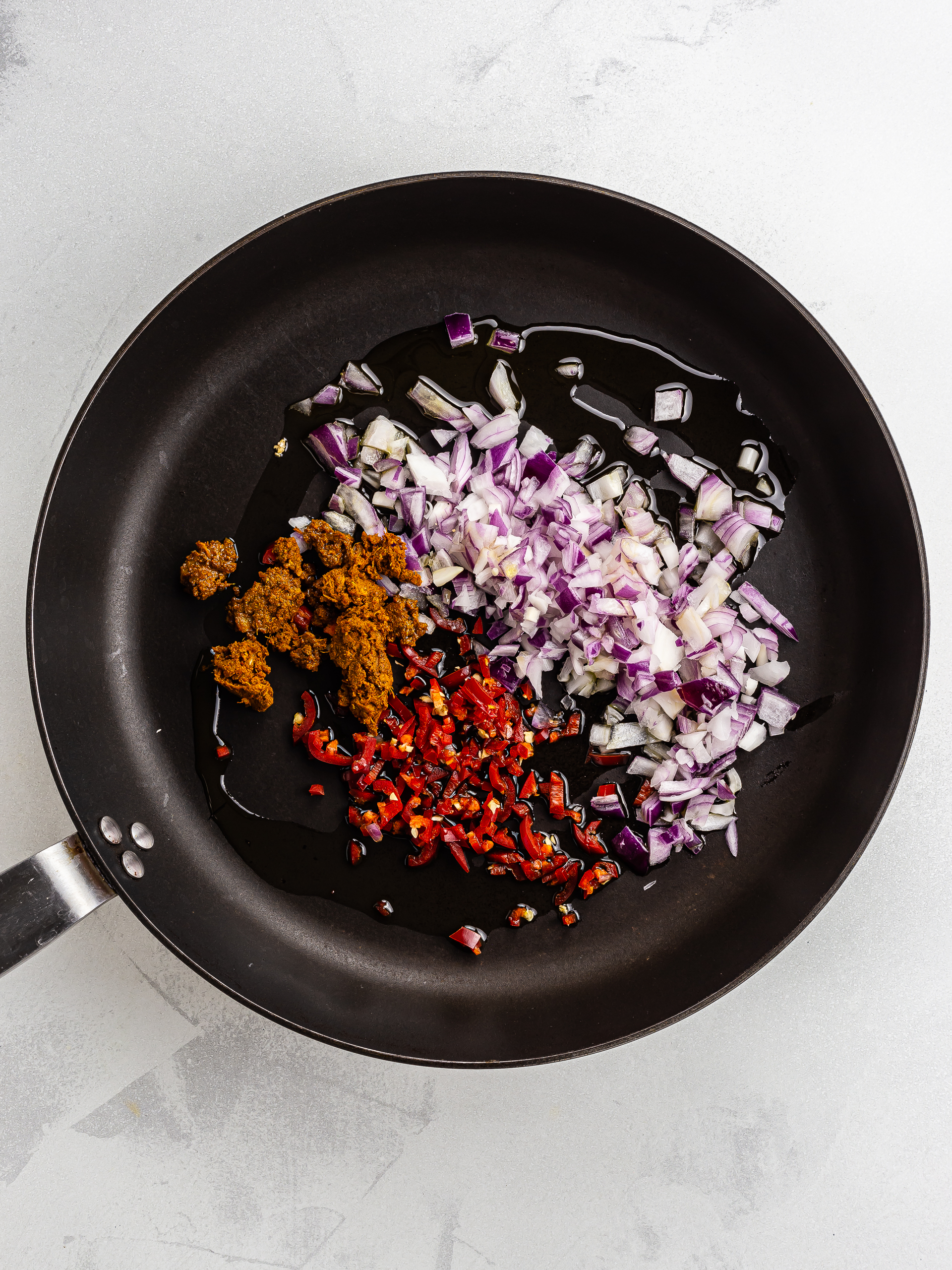 onions and chillies with tikka masala paste in skillet