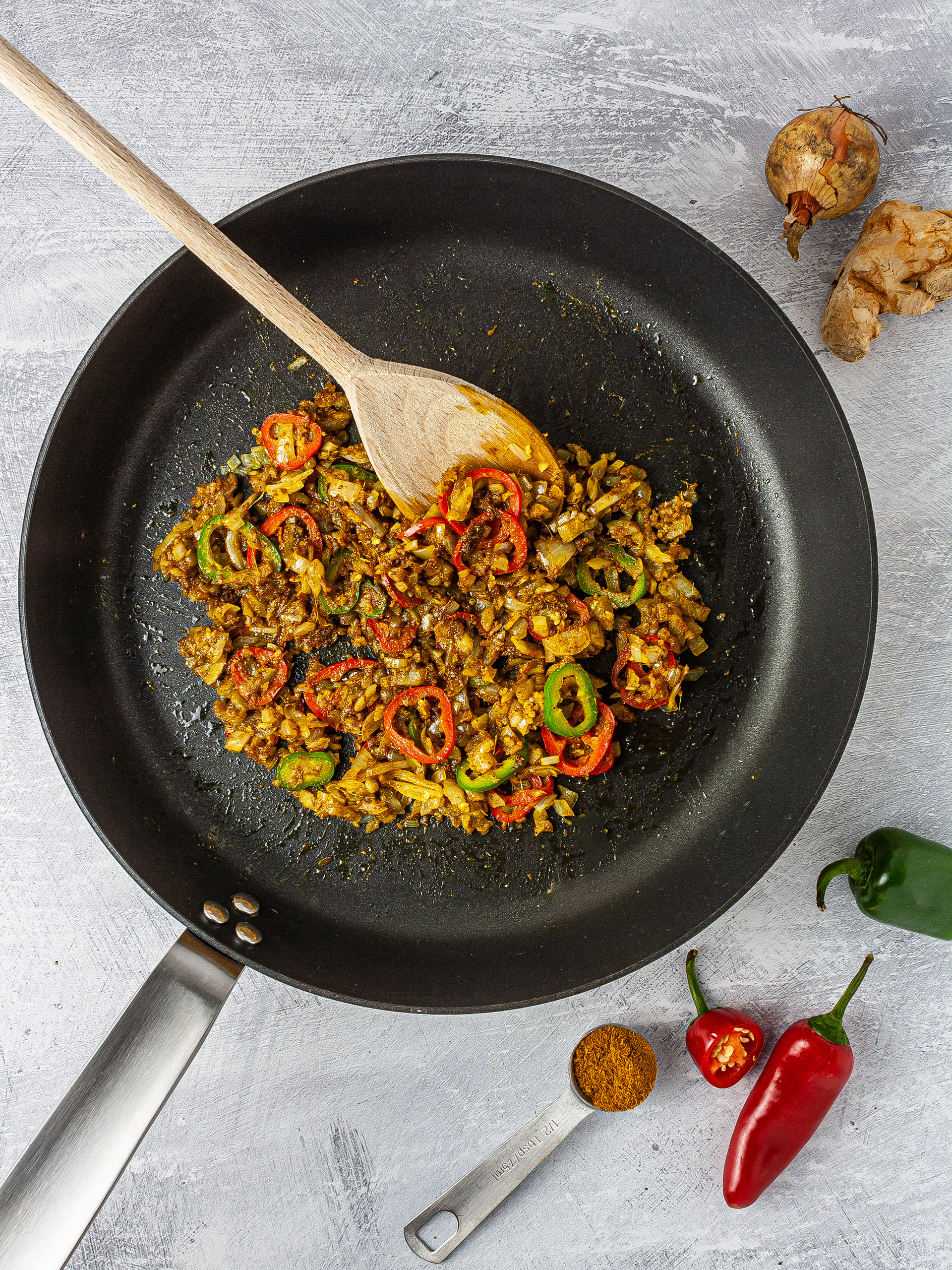 Onion, garlic, chillies, and curry powder sizzling in a pan.