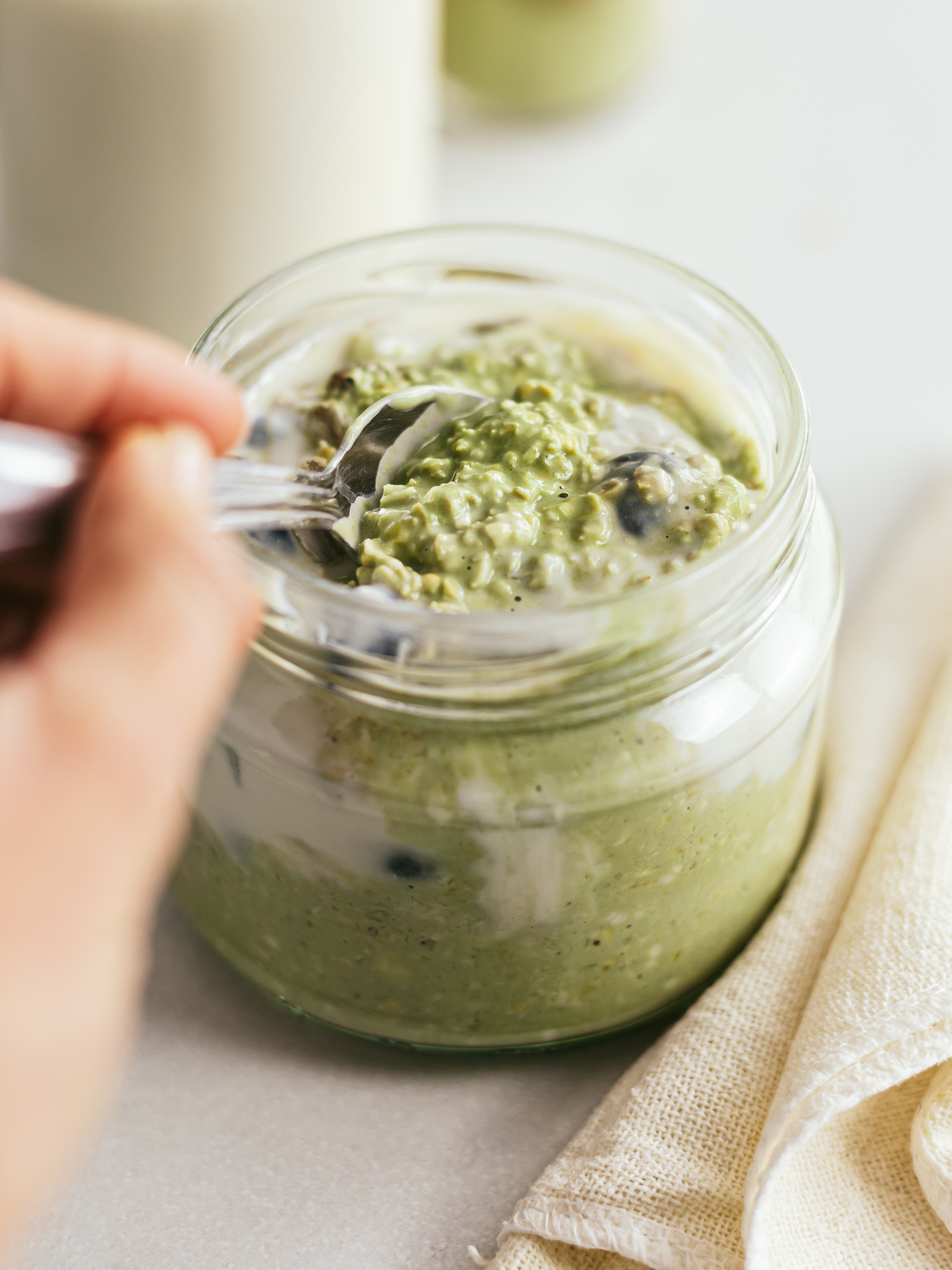 woman hand taking a spoonful of matcha oats