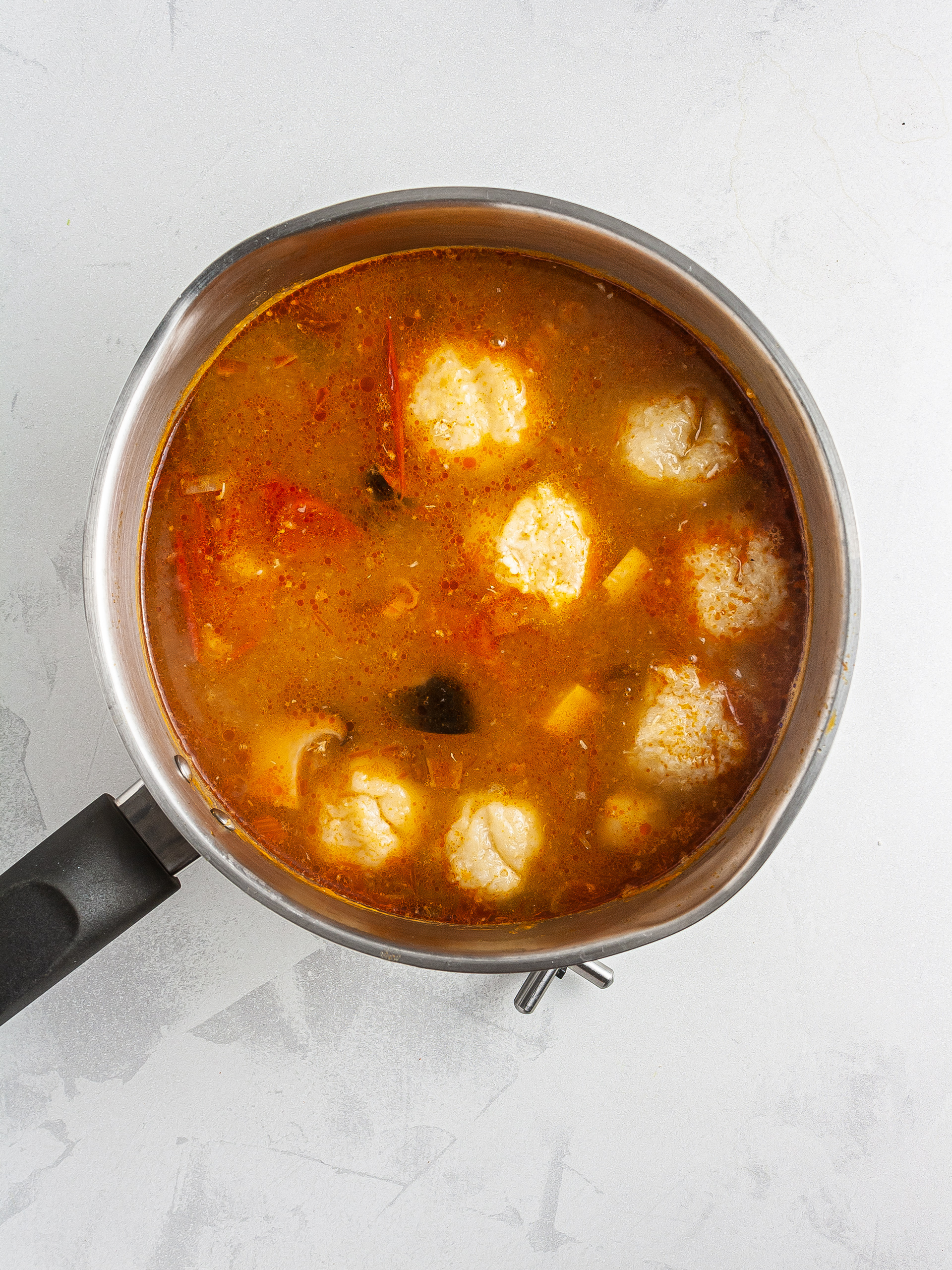 Crab balls in cooking in tomato stock