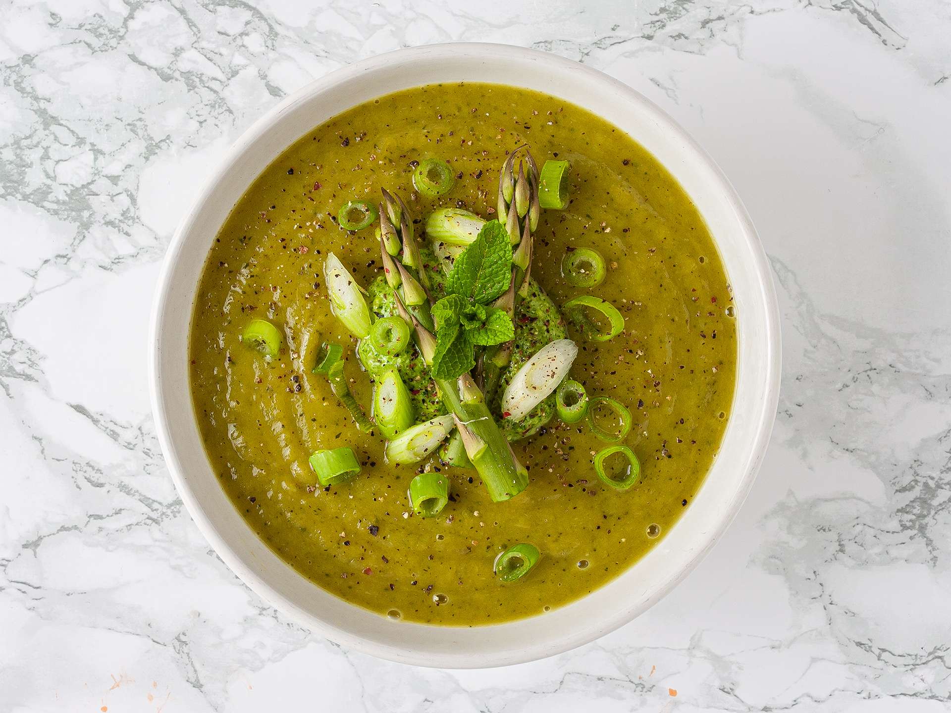 creamy asparagus and zucchini soup topped with watercress pesto, mint, and spring onions
