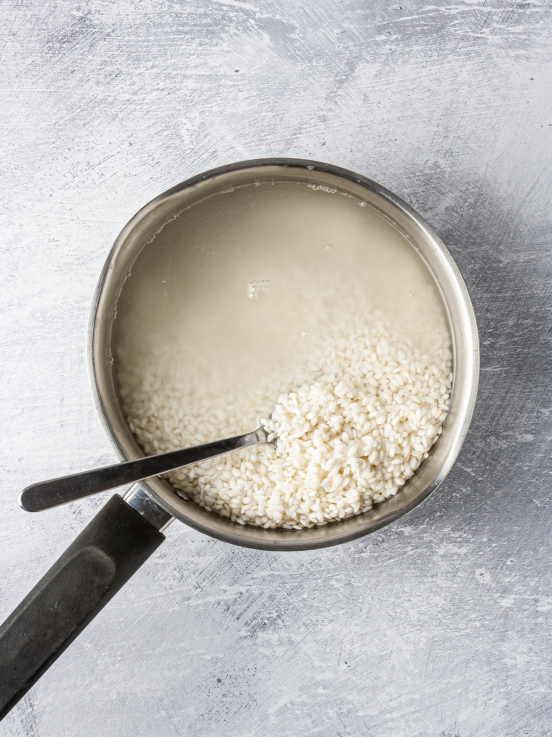 Sushi short grain rice cooking in a pan with water.